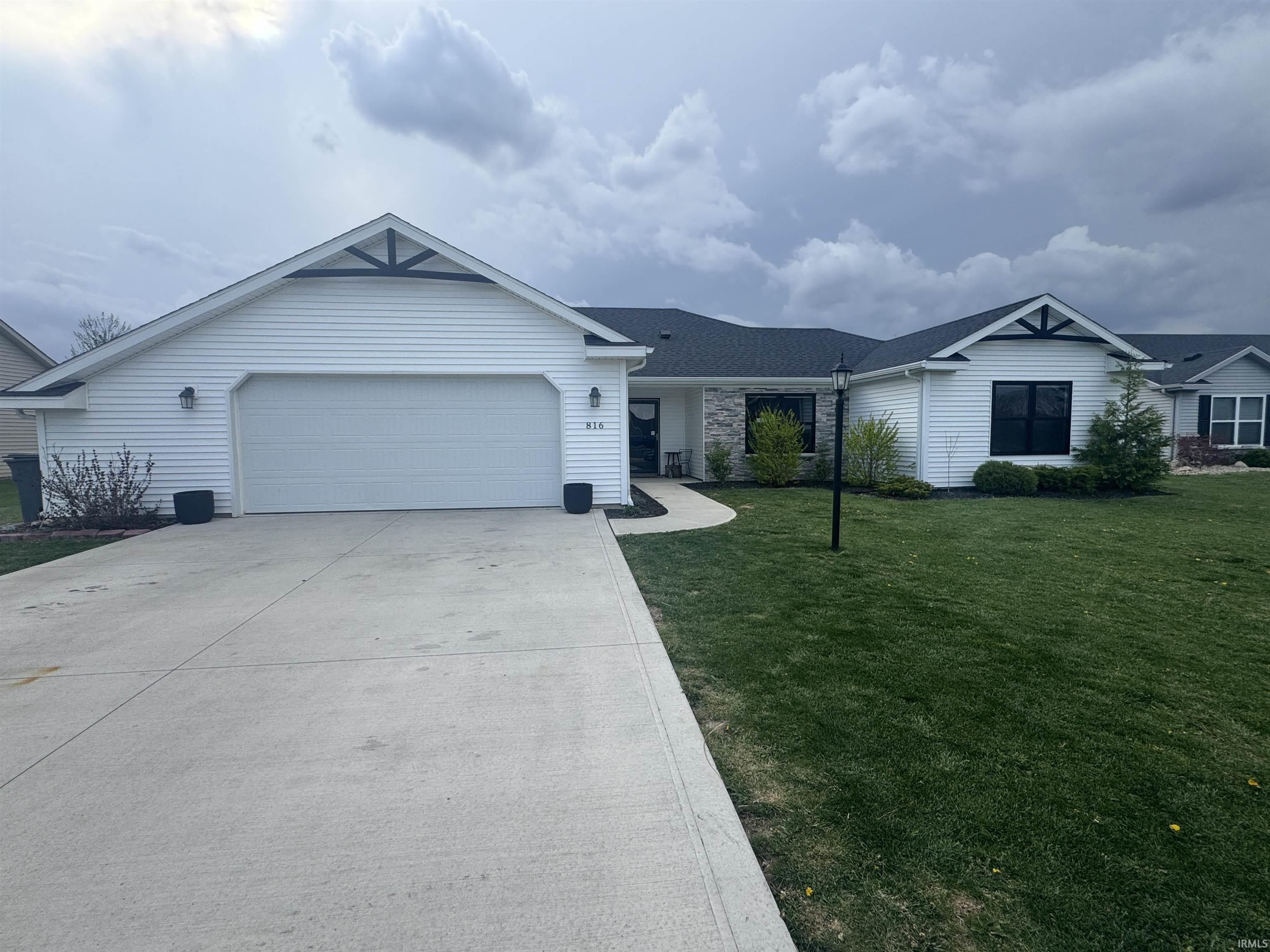 Ranch-style home with a garage, driveway, and a front lawn