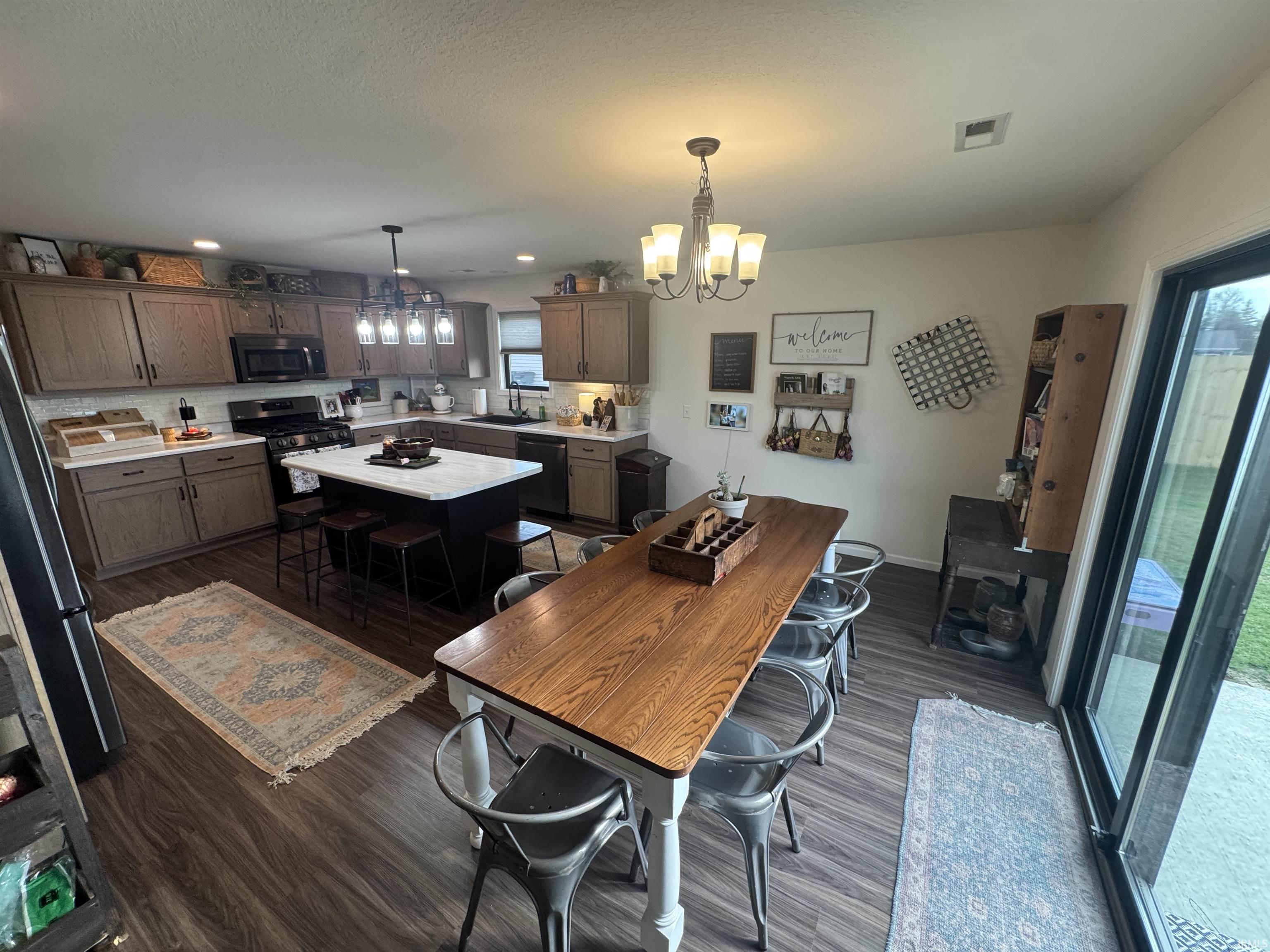 Dining area featuring hanging lights and dark wood-style flooring