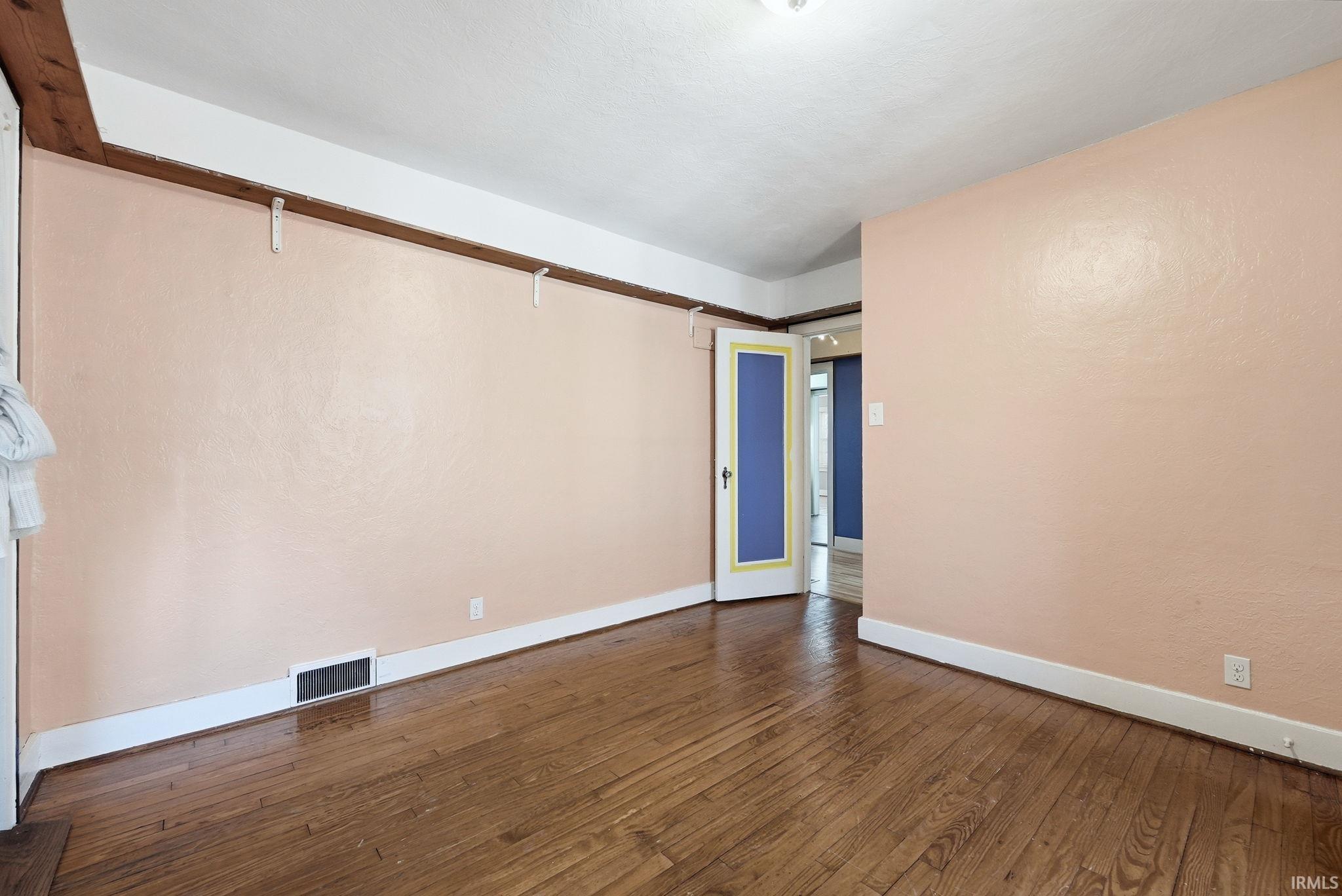 Unfurnished room with dark wood finished floors and baseboards