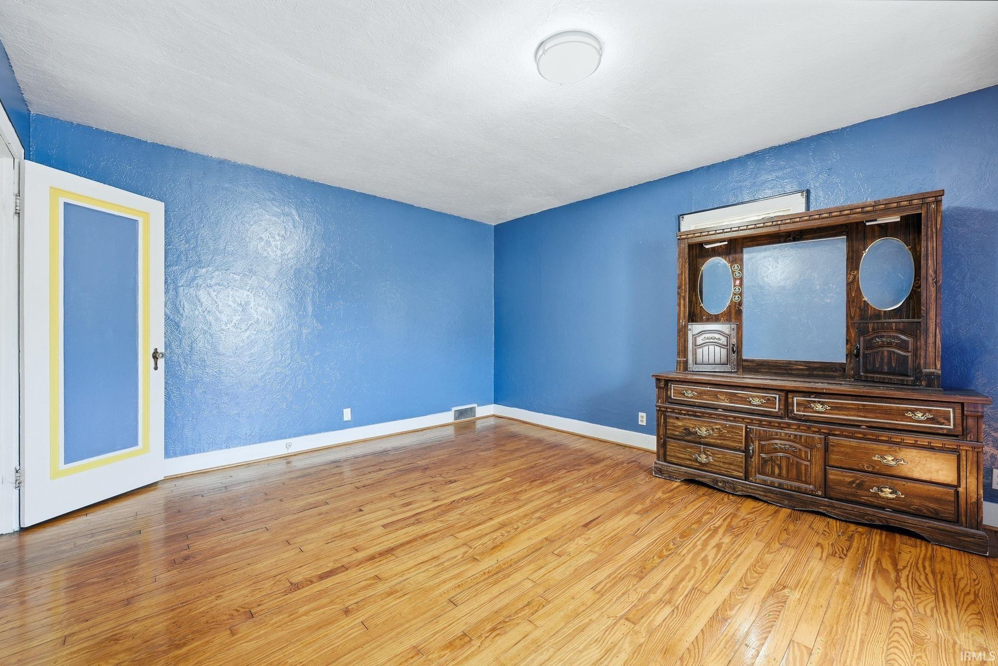 Unfurnished bedroom with a textured wall and light wood finished floors