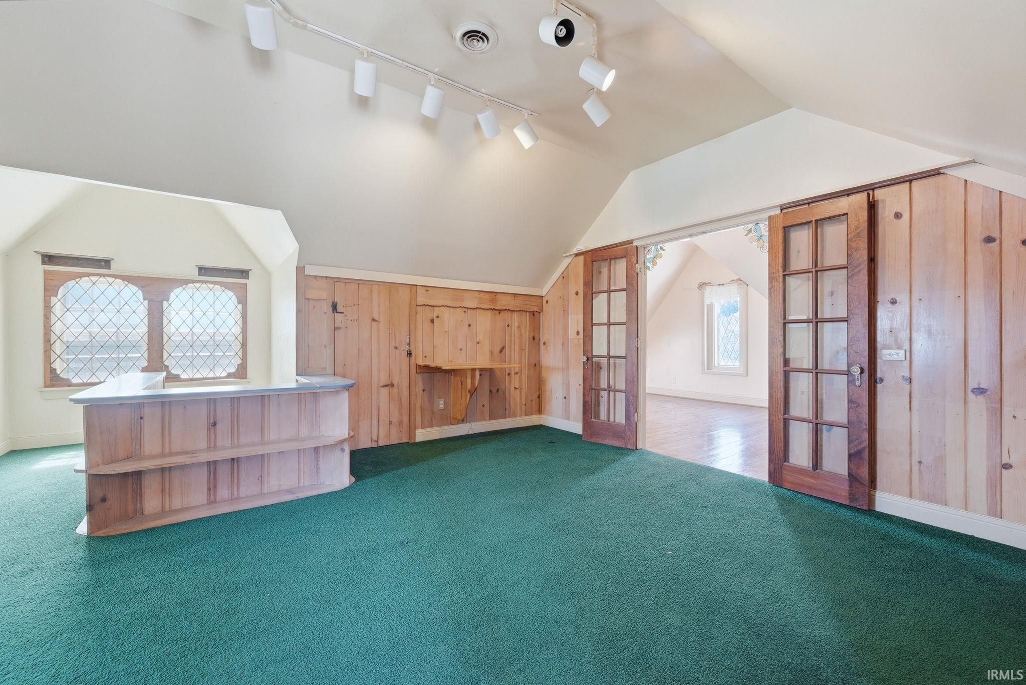 Additional living space with french doors, wooden walls, and carpet flooring