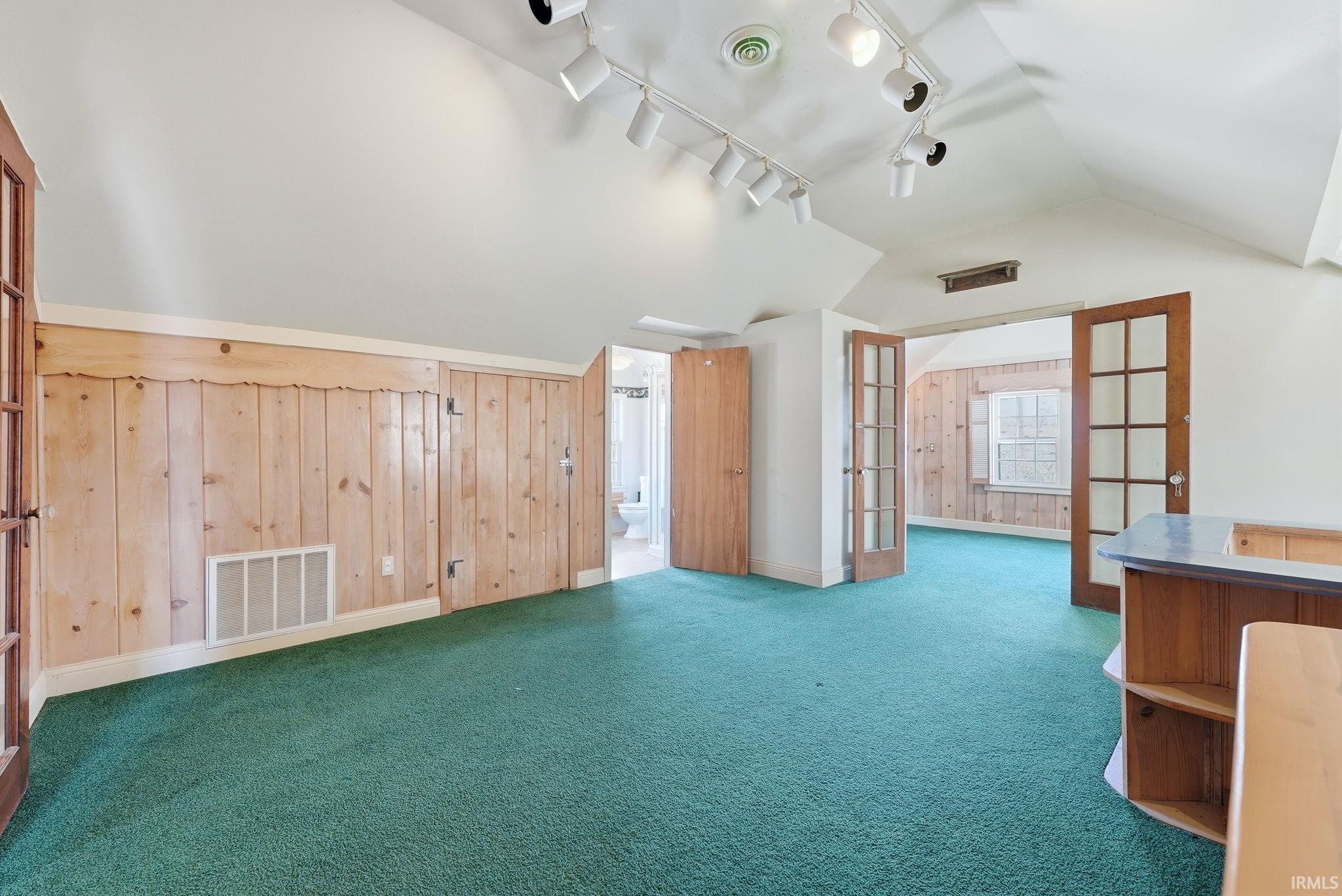 Bonus room featuring french doors, wood walls, and carpet flooring