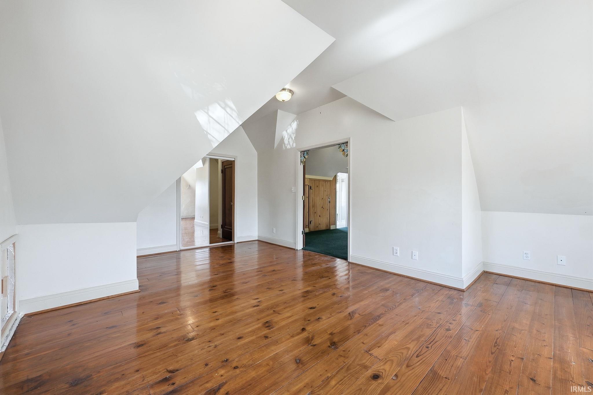 Additional living space featuring vaulted ceiling and dark wood-style flooring
