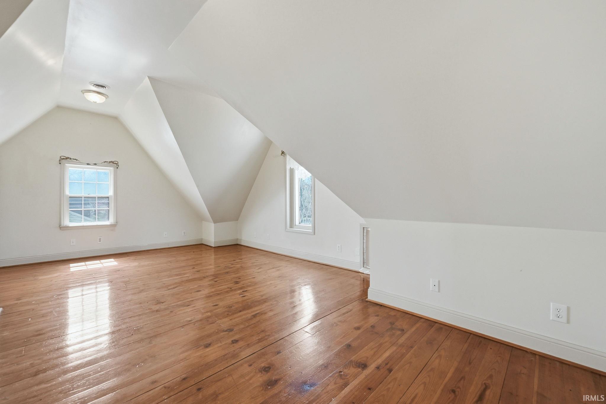 Bonus room with vaulted ceiling, light wood finished floors, and healthy amount of natural light