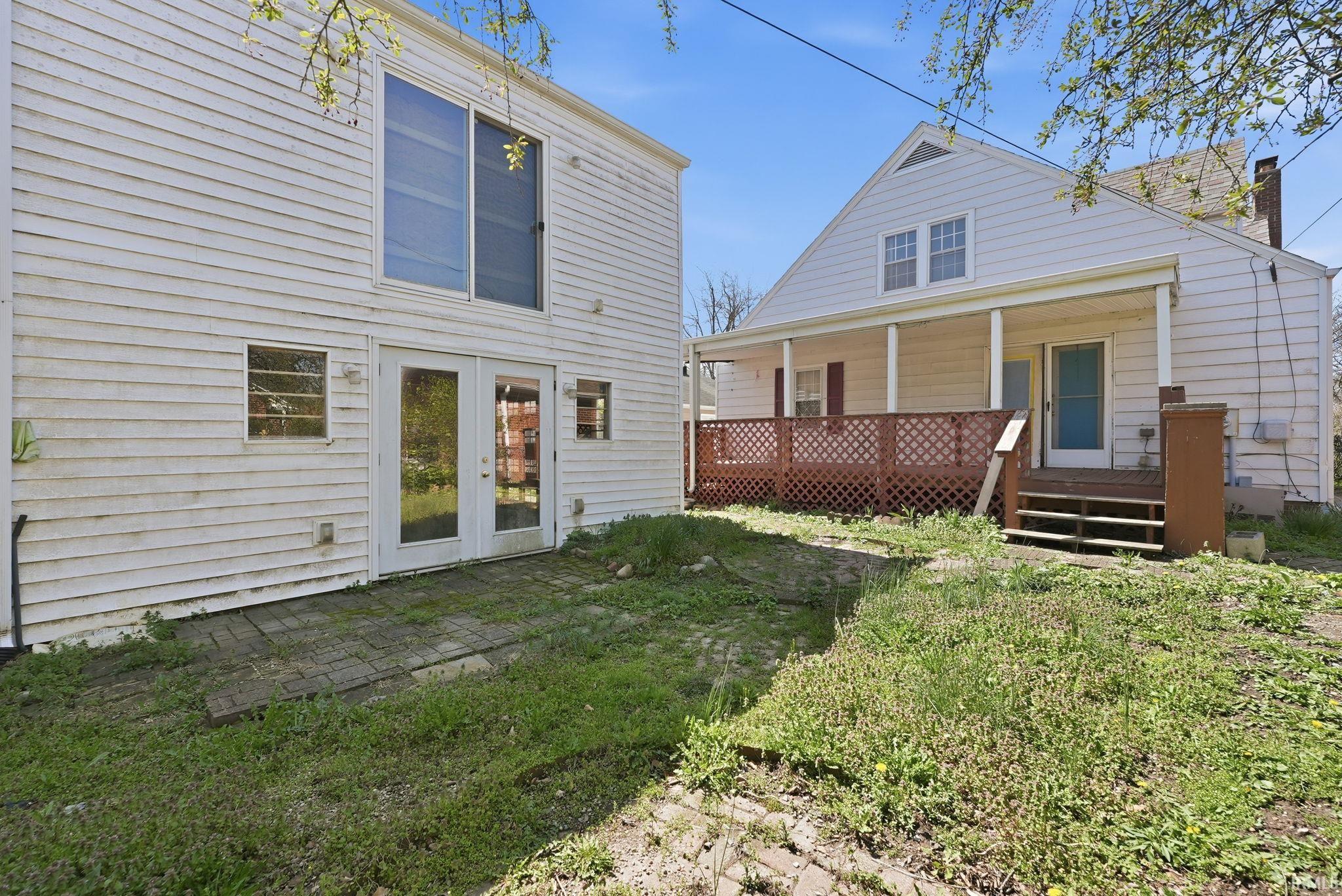 Rear view of property with covered porch, a chimney, and french doors