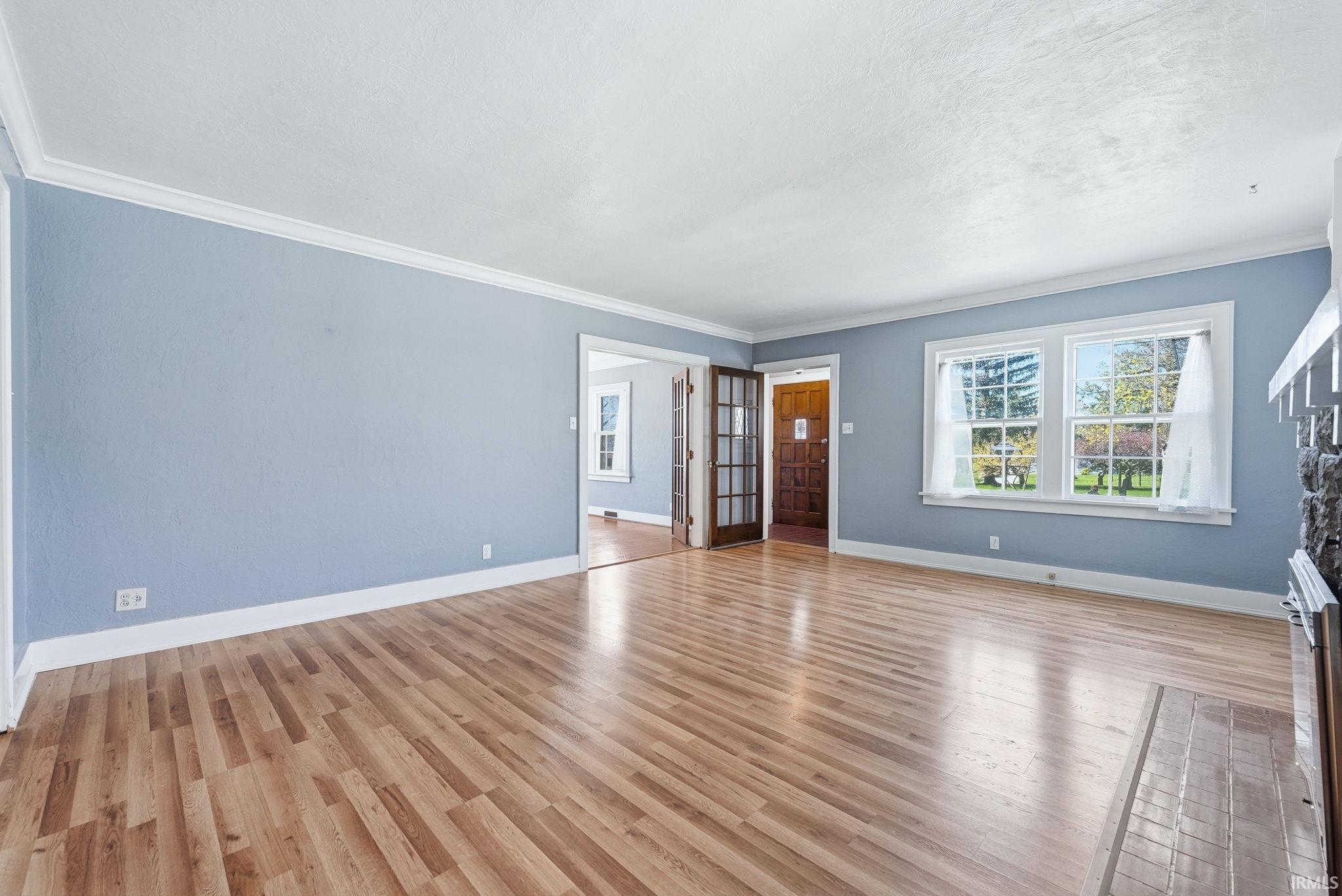 Unfurnished living room with crown molding and light wood-style flooring