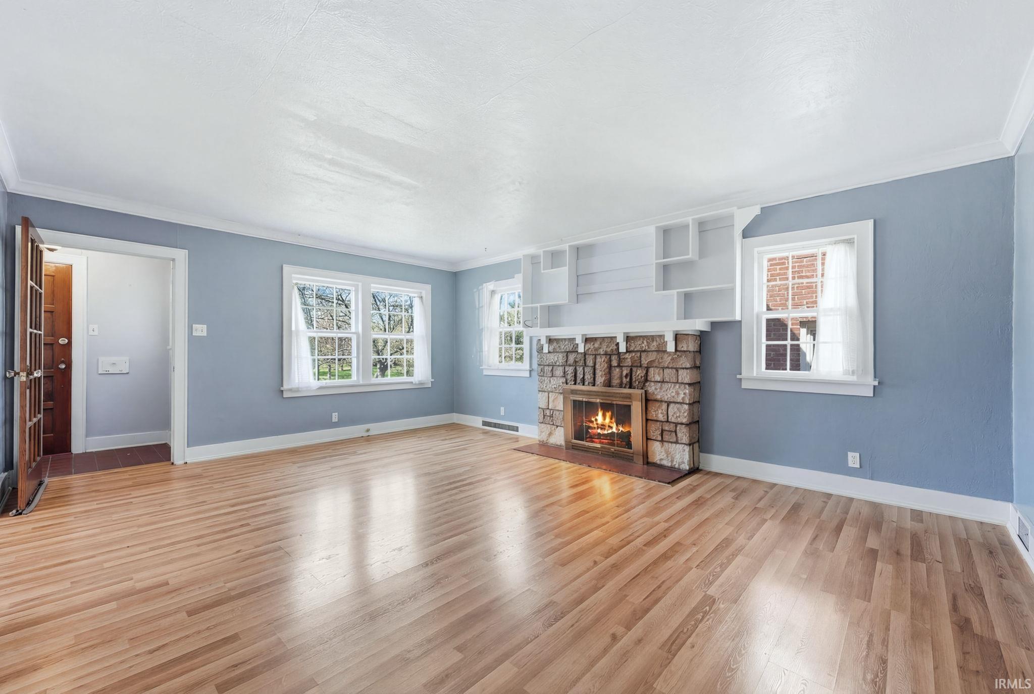 Unfurnished living room with crown molding, a fireplace, and light wood-type flooring