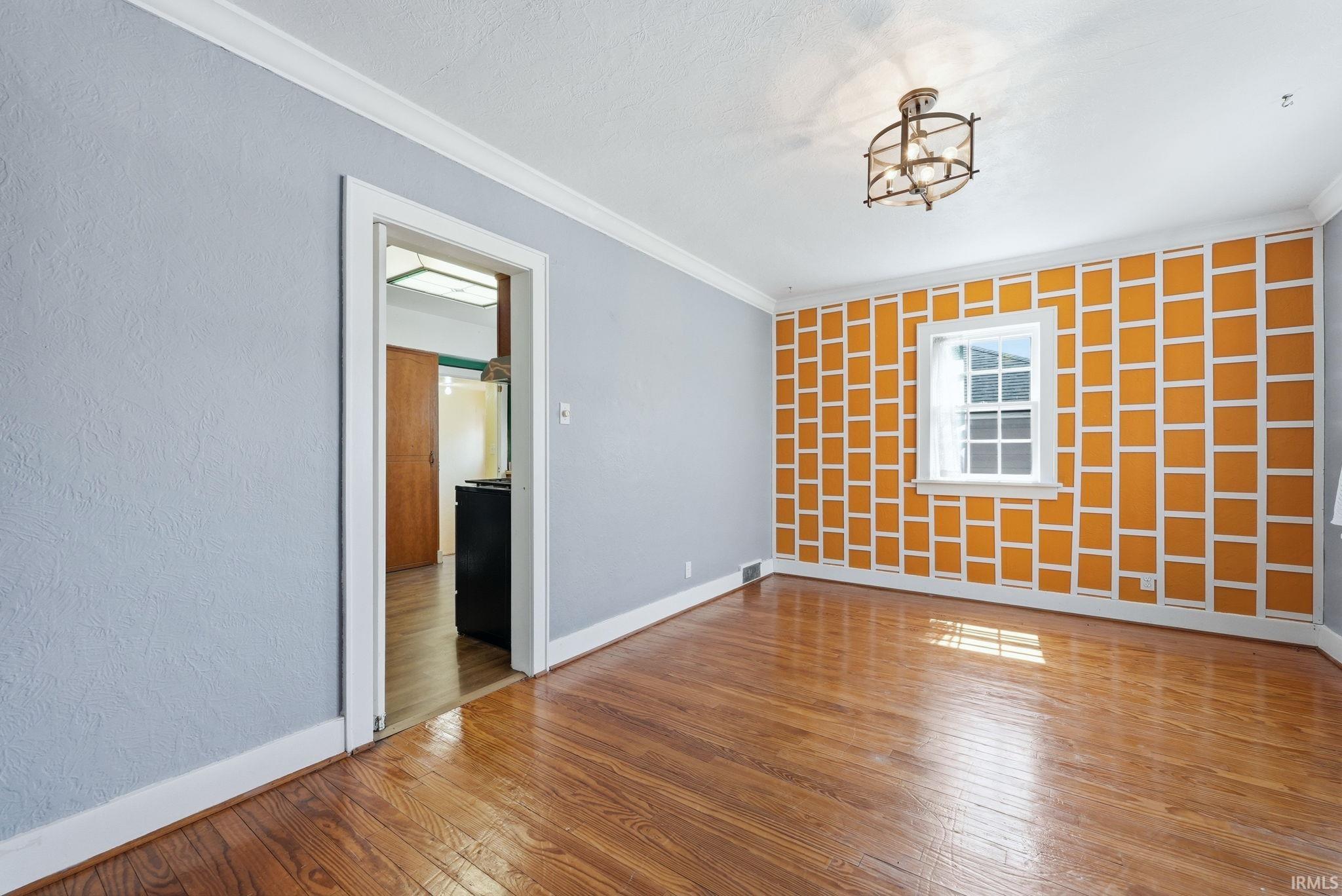 Unfurnished room featuring wood-type flooring and crown molding