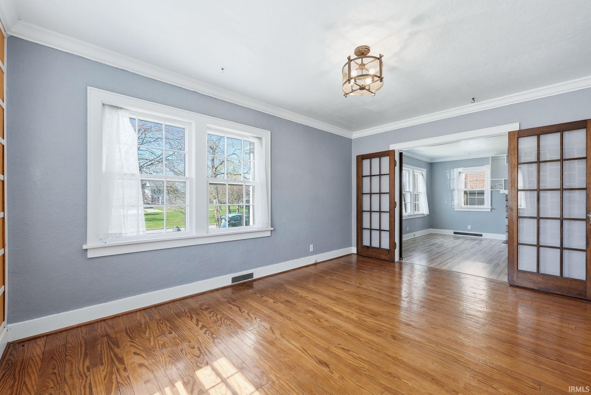Unfurnished room with light wood-style flooring, french doors, and ornamental molding