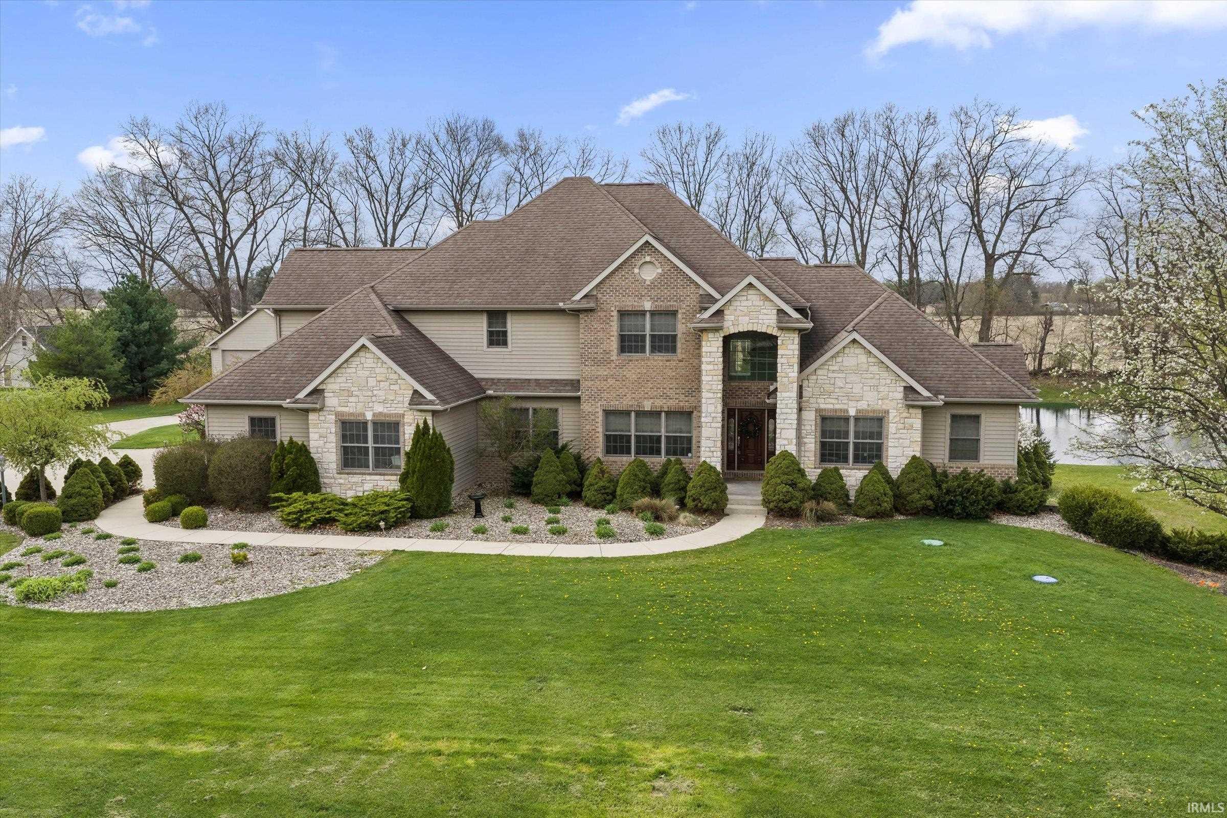 View of front of home featuring stone siding, a front yard, and a shingled roof
