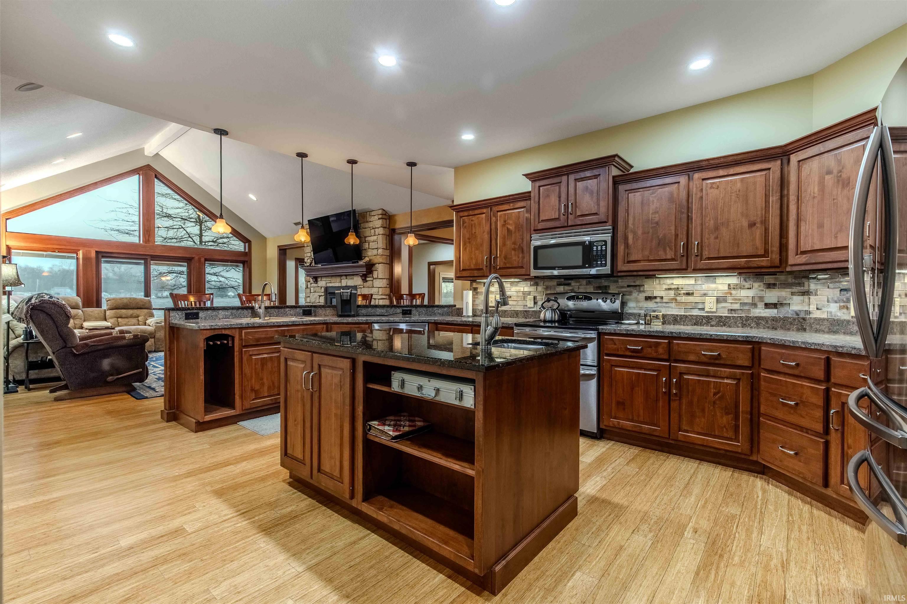 Custom Kitchen featuring stainless steel appliances, dark granite counters, a peninsula w/island, Grabill hand crafted cabinets, and custom backsplash