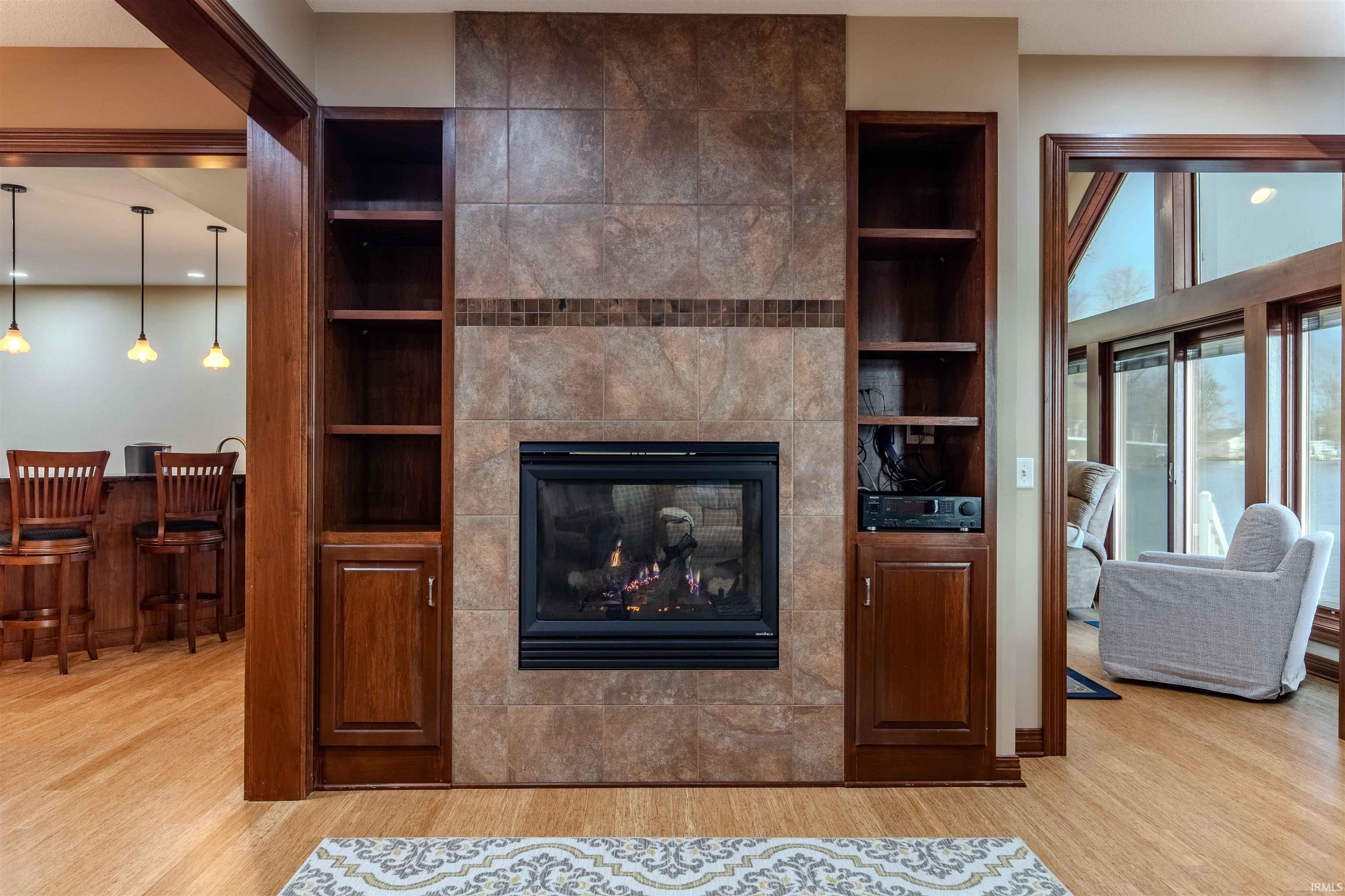 Living area featuring the dual view / sided fireplace W/custom mantle, TV & Harmon / Kardon soundbar.