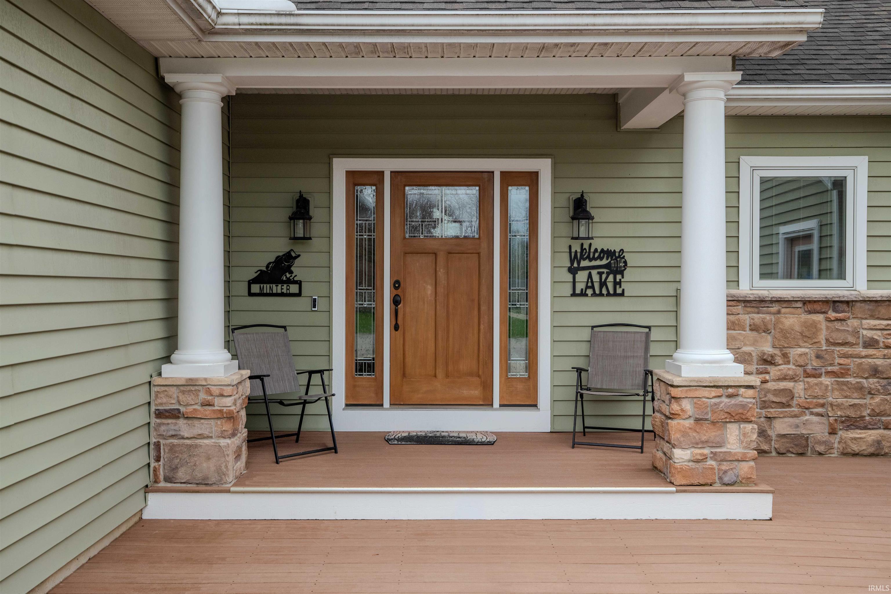 View of exterior entry featuring covered porch and stone siding