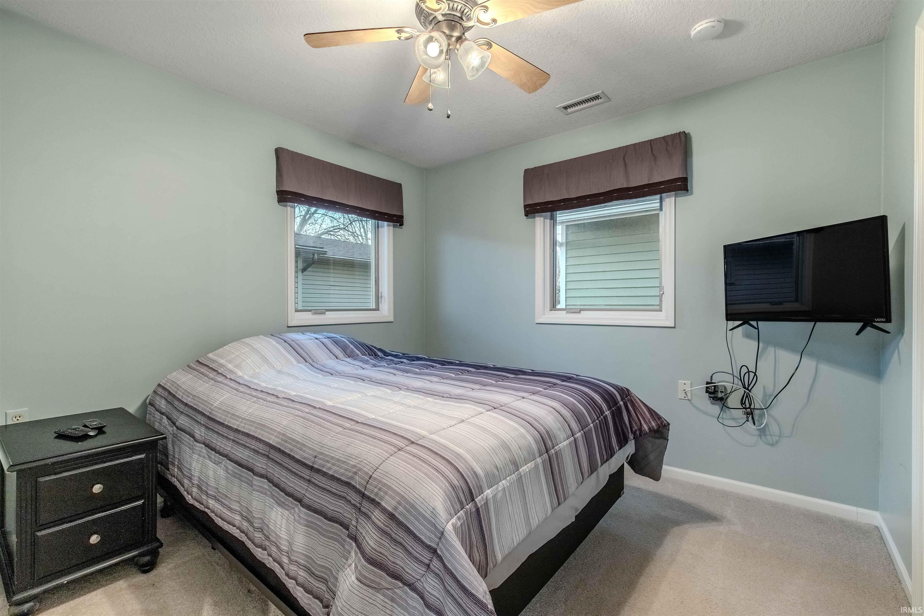 Bedroom with light carpet and a ceiling fan