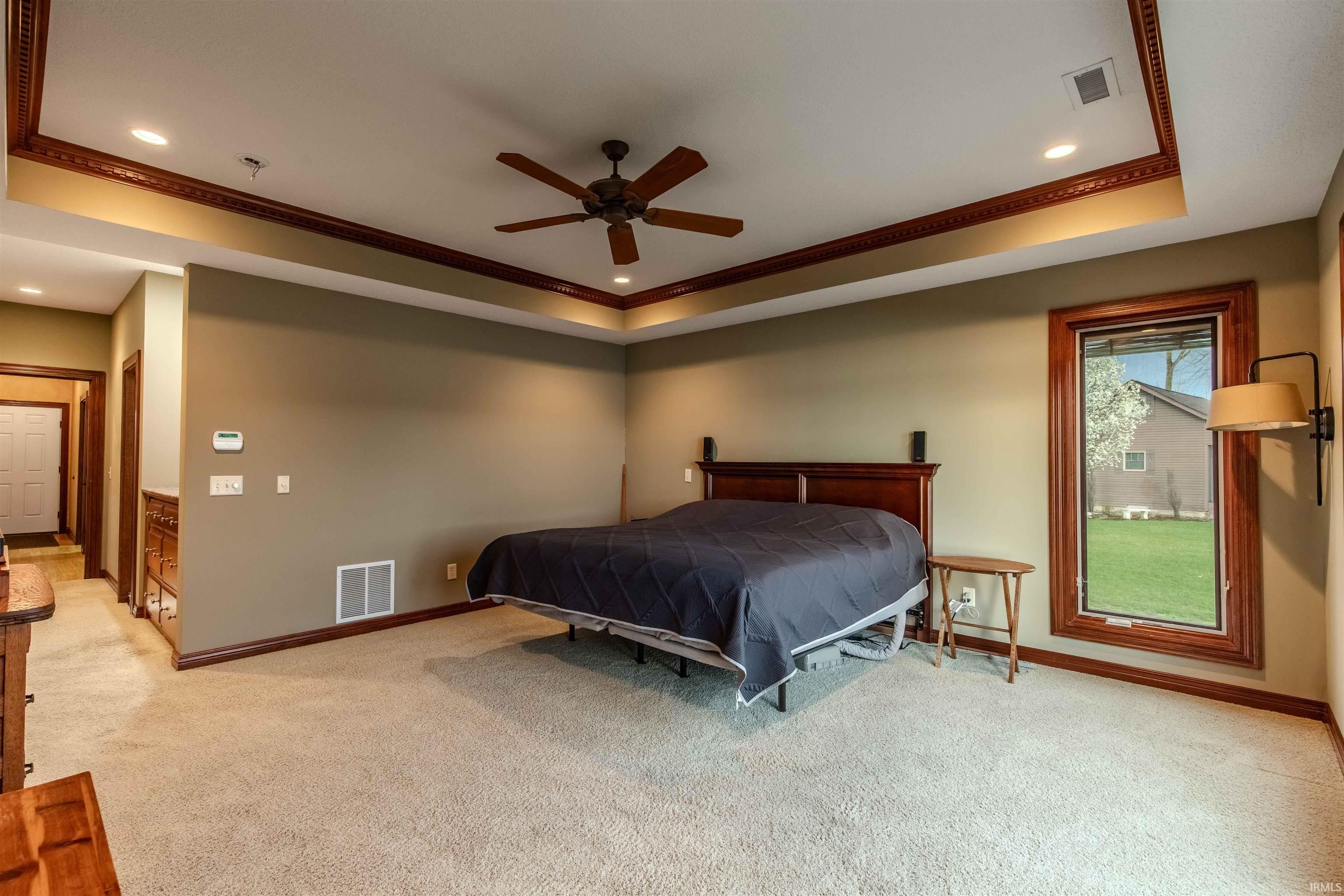 Featuring a tray ceiling, ornamental custom moldings, recessed lighting, and a stunning view of the lake to wake up to.