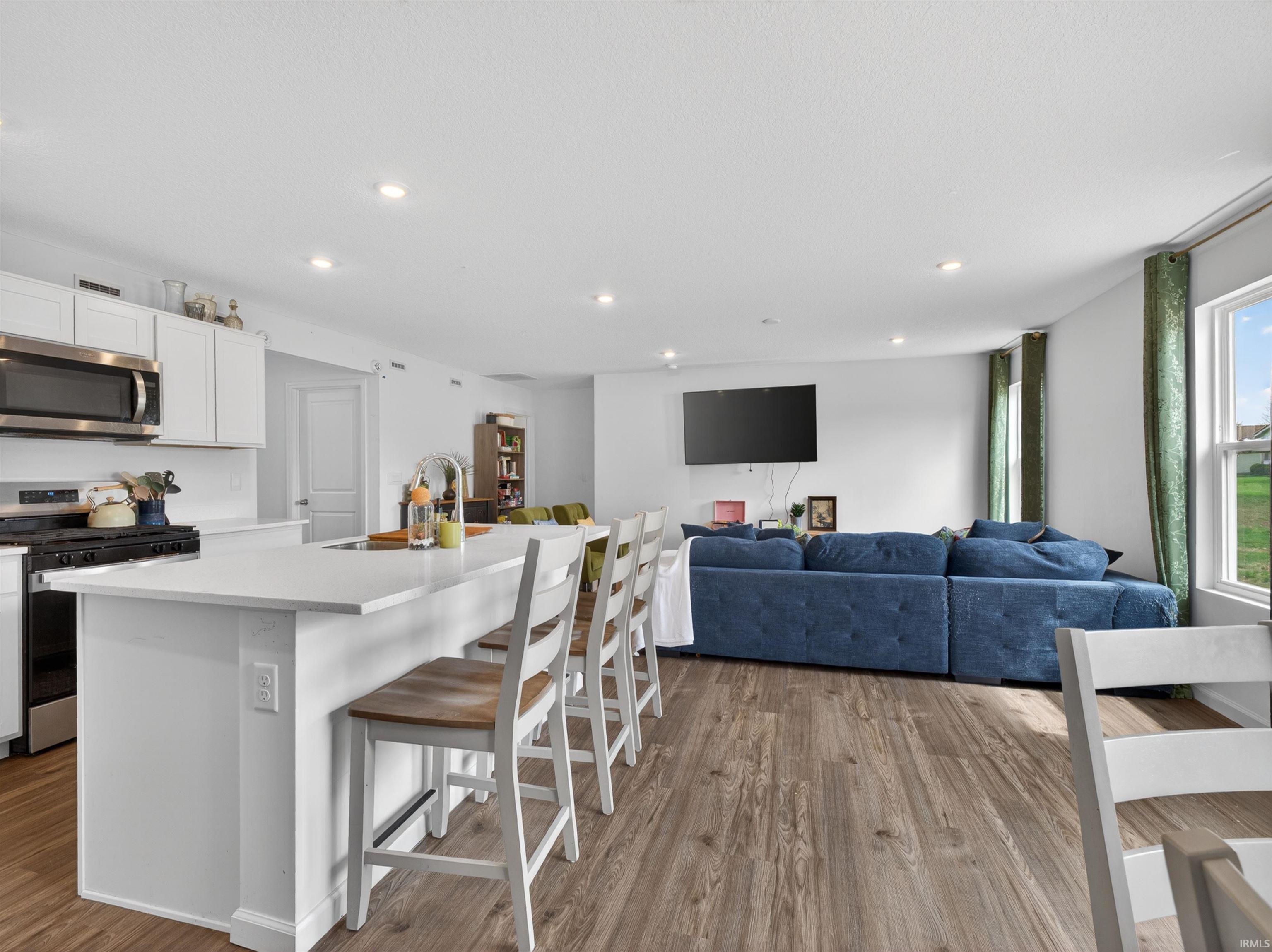Kitchen with a kitchen island with sink, stainless steel appliances, a breakfast bar, white cabinets, and open floor plan