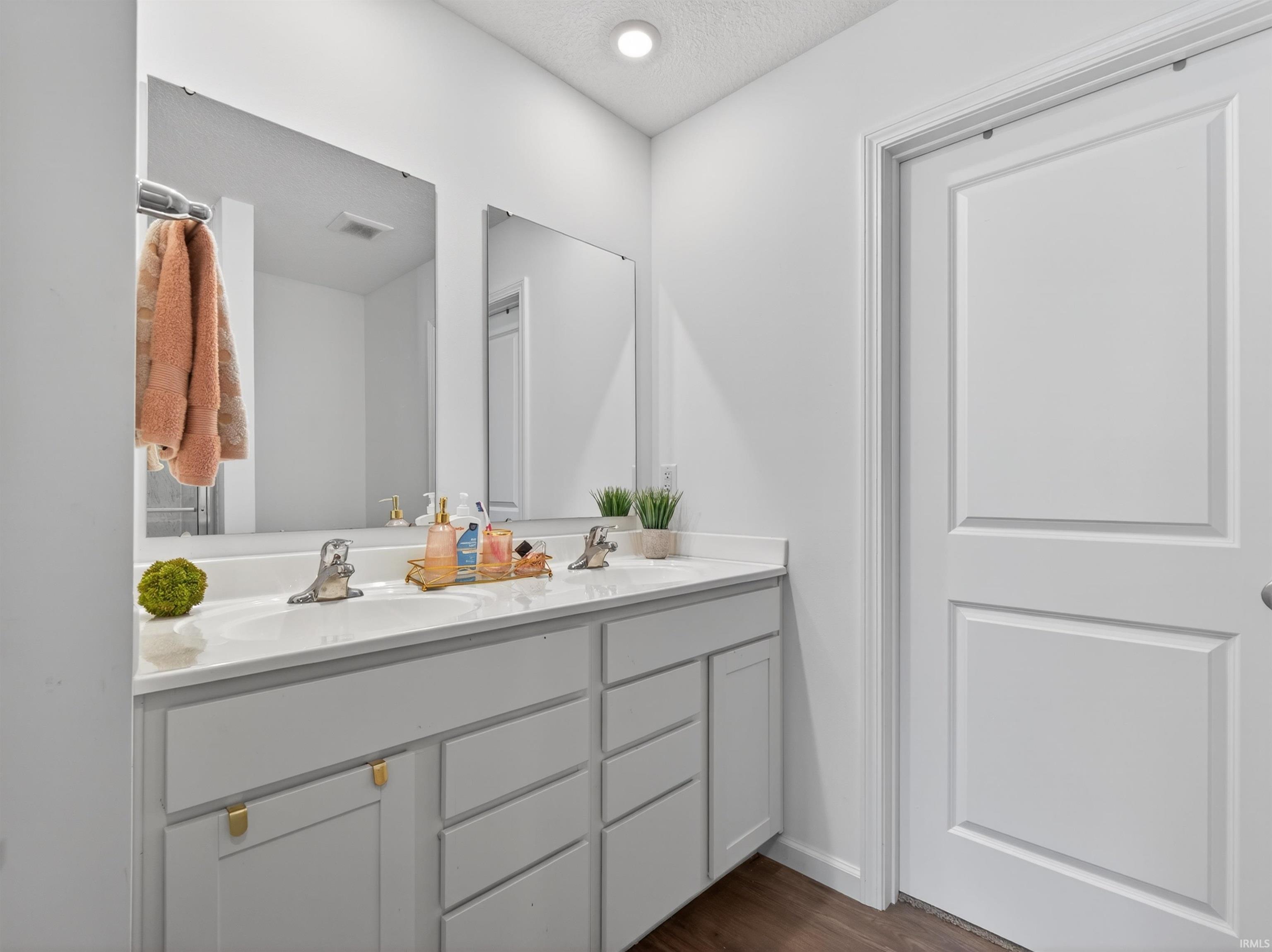 Bathroom featuring double vanity, dark wood-style floors, and a textured ceiling