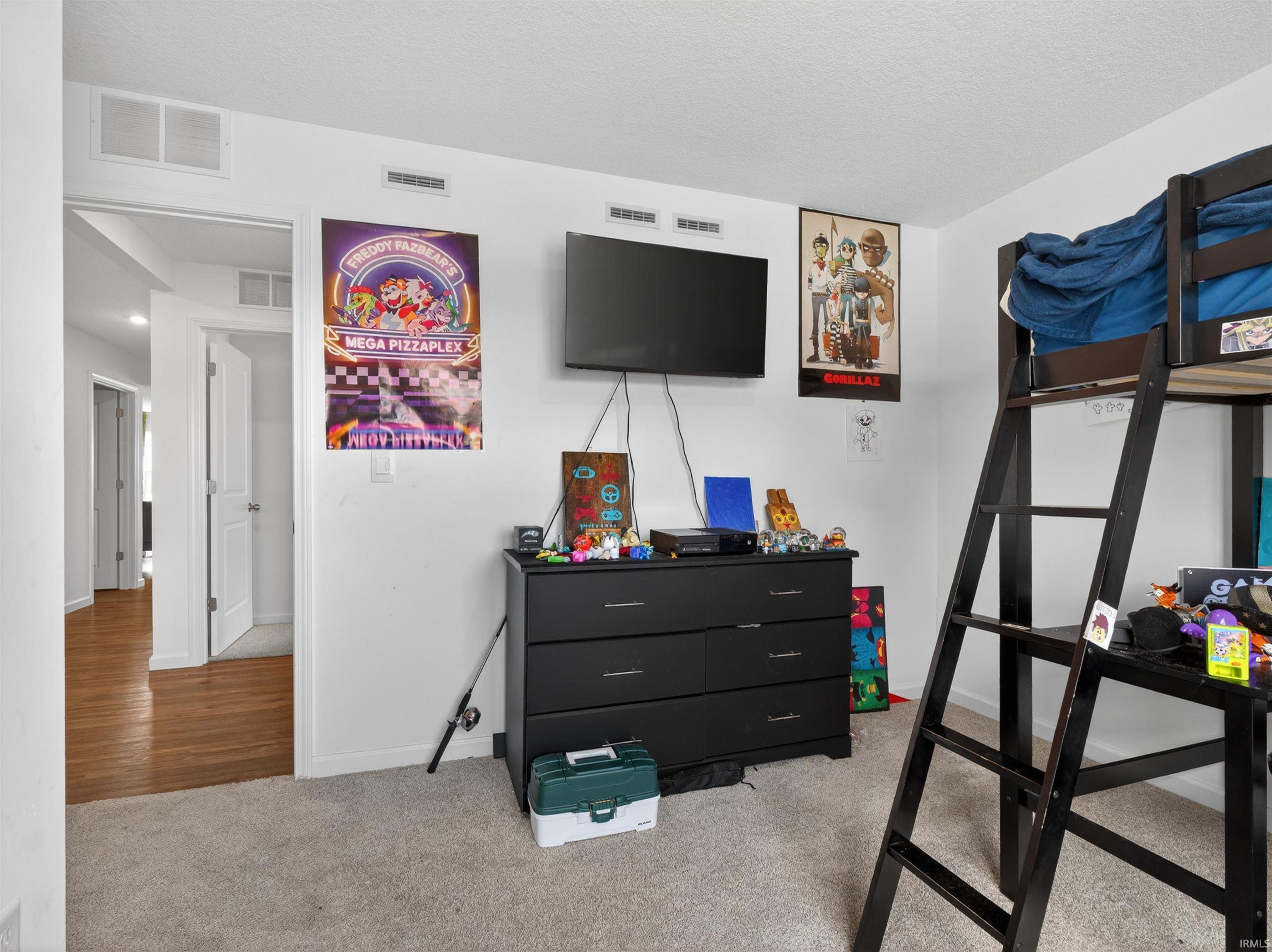 Bedroom with light colored carpet and a textured ceiling