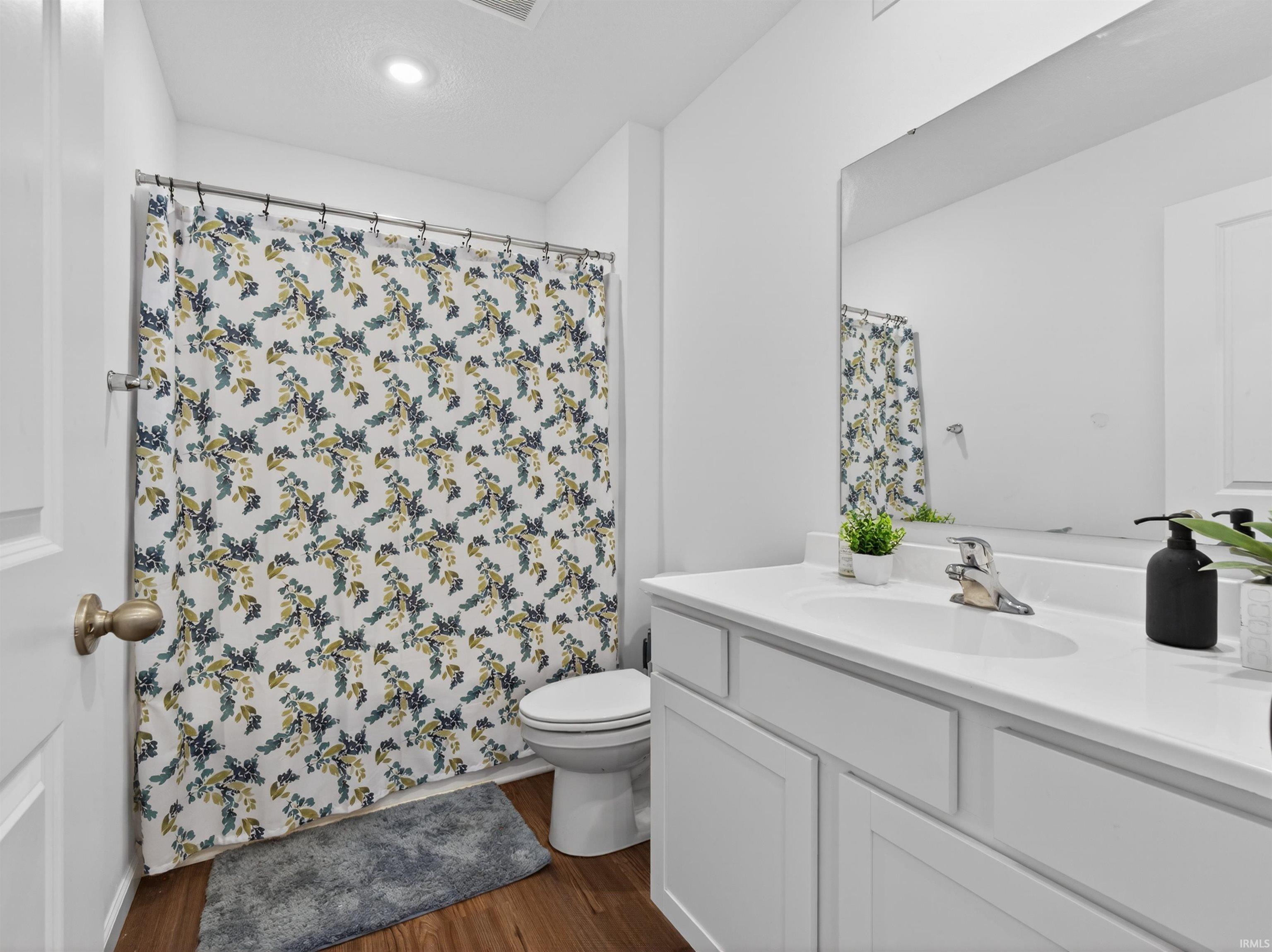 Full bathroom featuring vanity, dark wood finished floors, and a shower with curtain