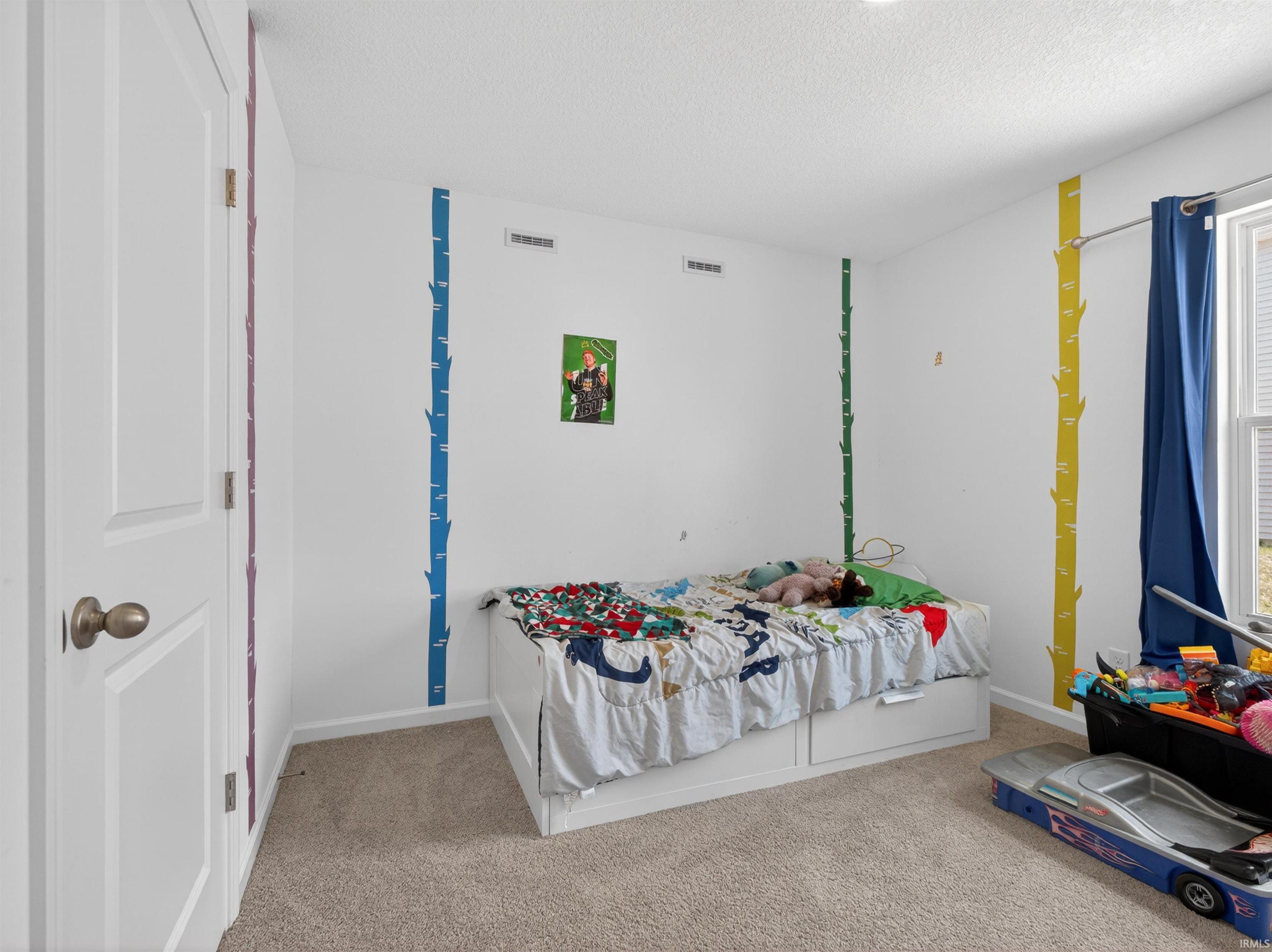 Bedroom with light carpet and a textured ceiling