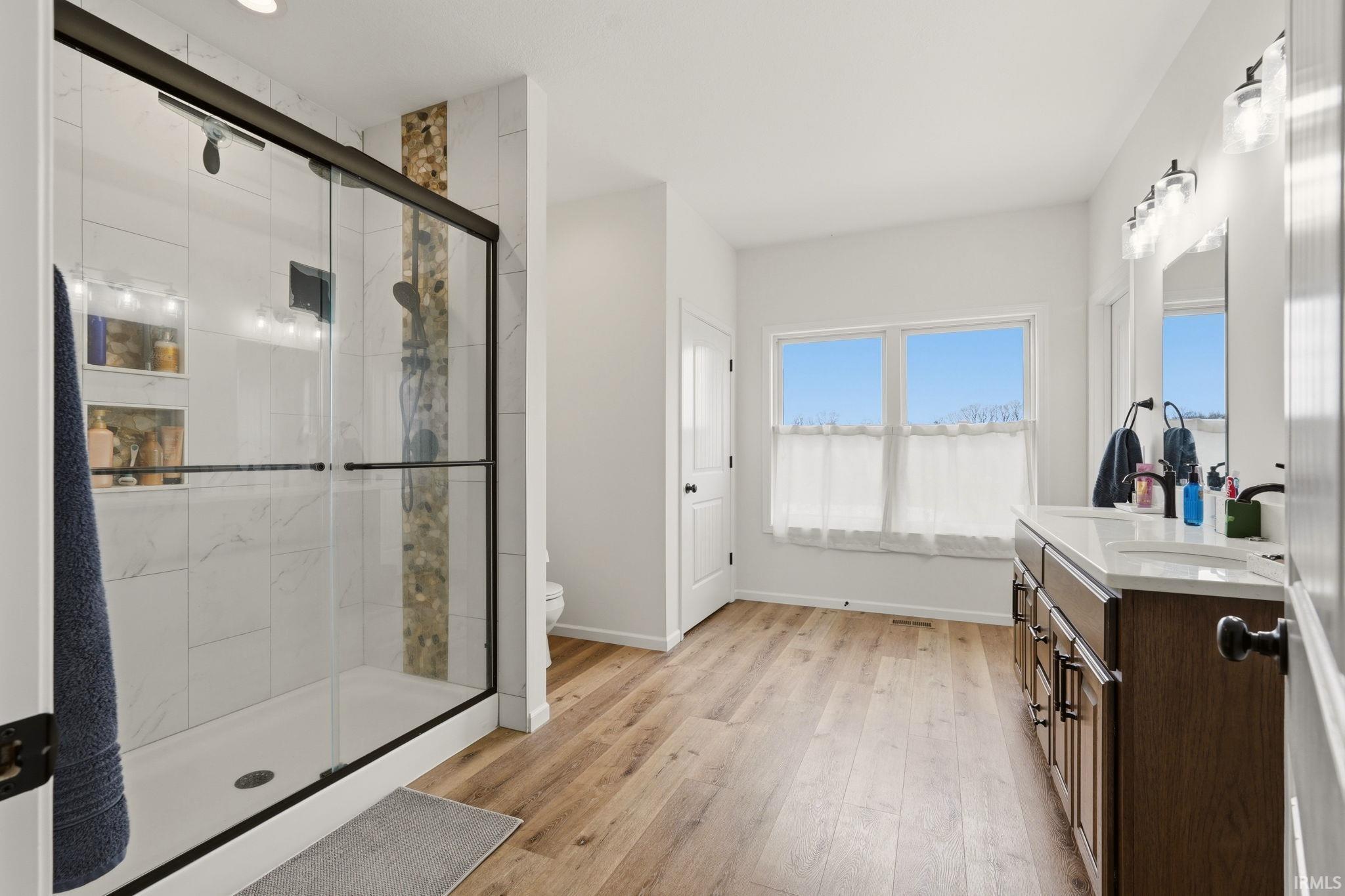 Bathroom with vanity, a shower stall, and light wood-type flooring