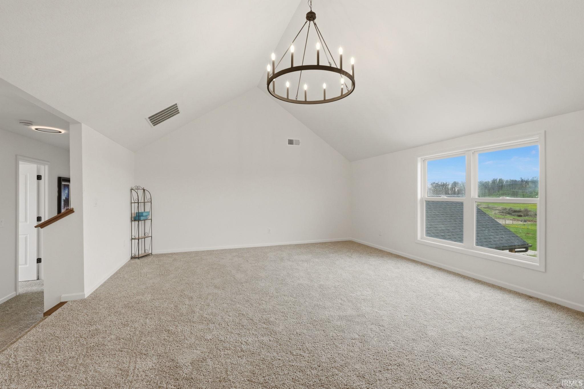 Additional living space featuring light carpet and hanging lights