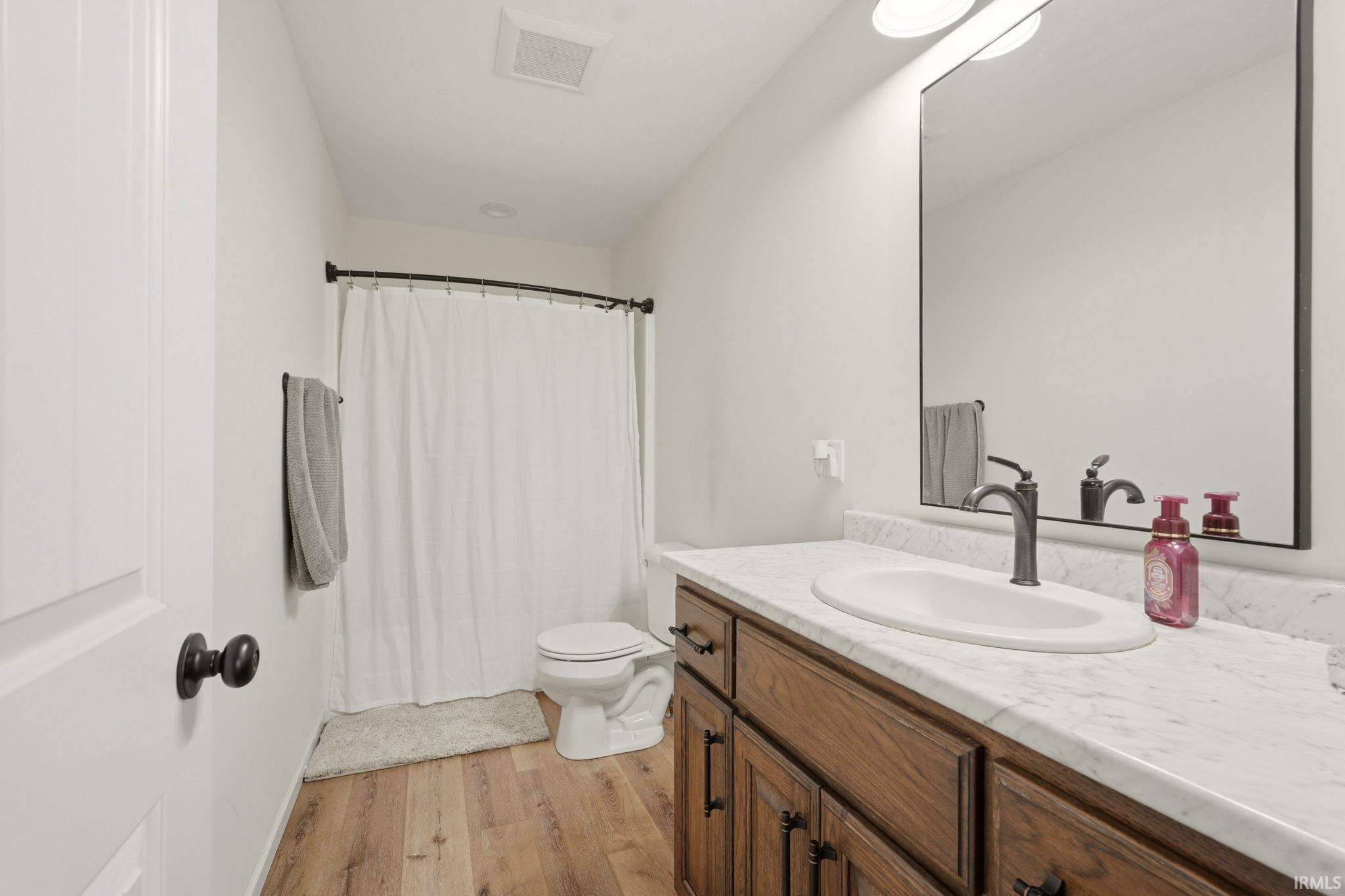 Full bath featuring vanity, light wood-type flooring, and curtained shower