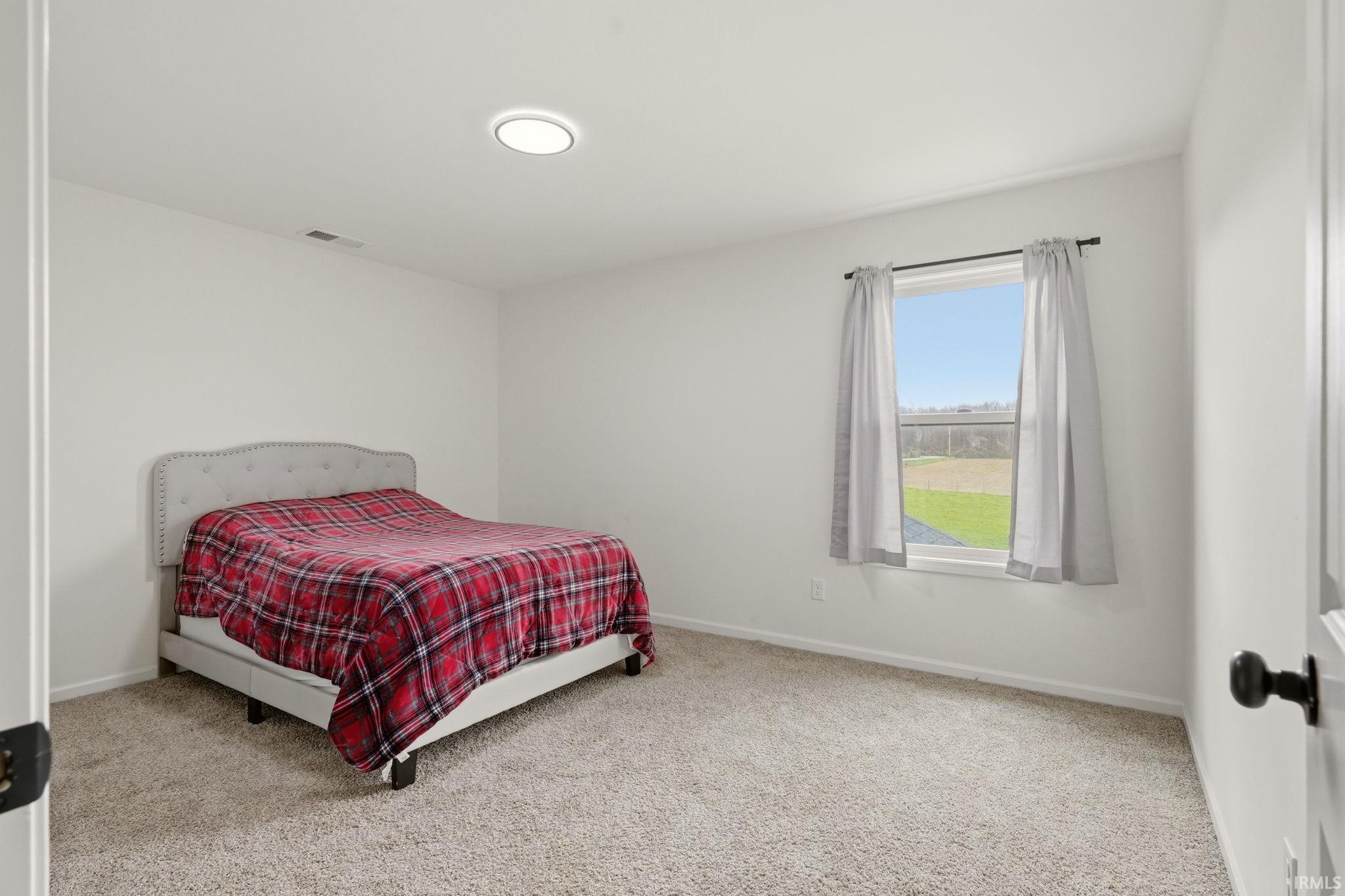 Bedroom with light colored carpet and baseboards