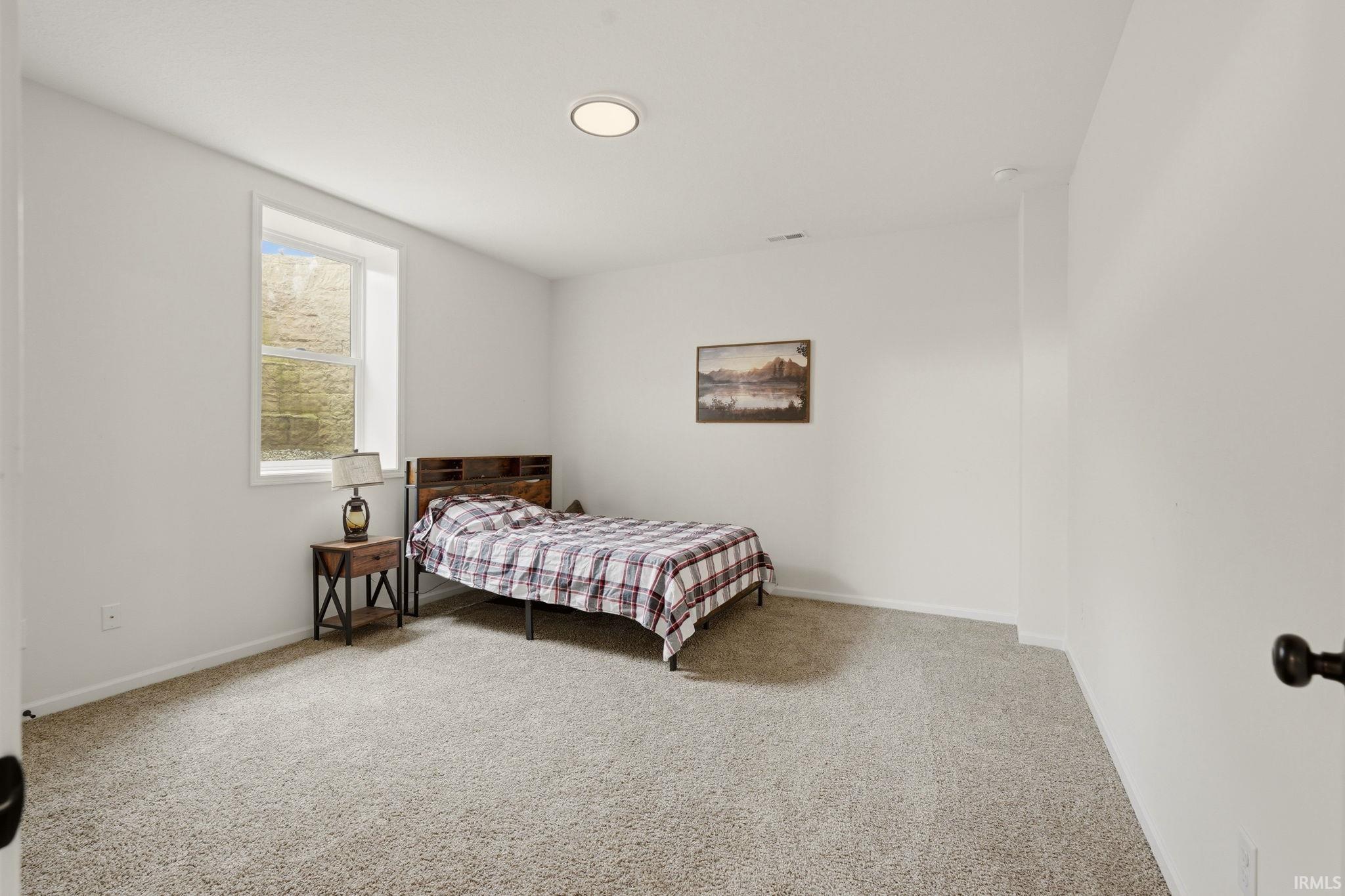 Bedroom featuring light carpet and baseboards