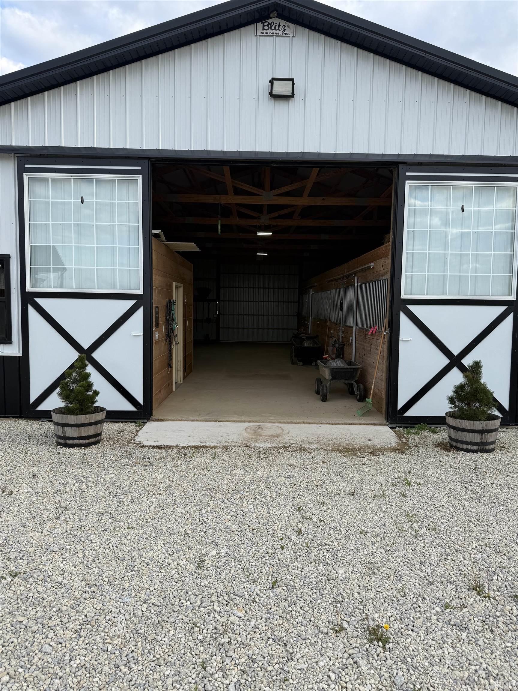 Large white metal-sided barn featuring a black gable roof and trim