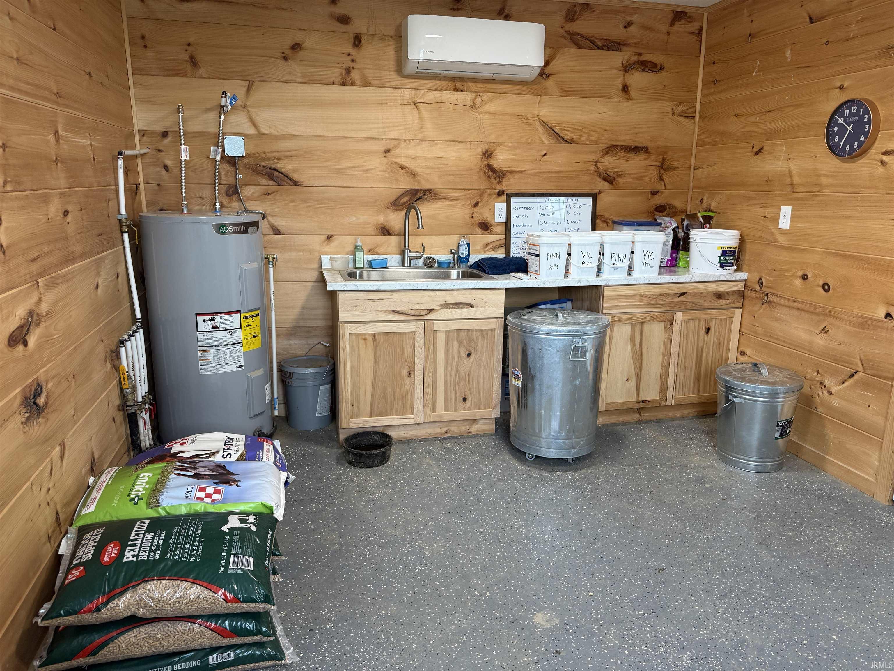 Tackroom featuring wood plank wall finishing, a water heater, and a mini-split HVAC unit