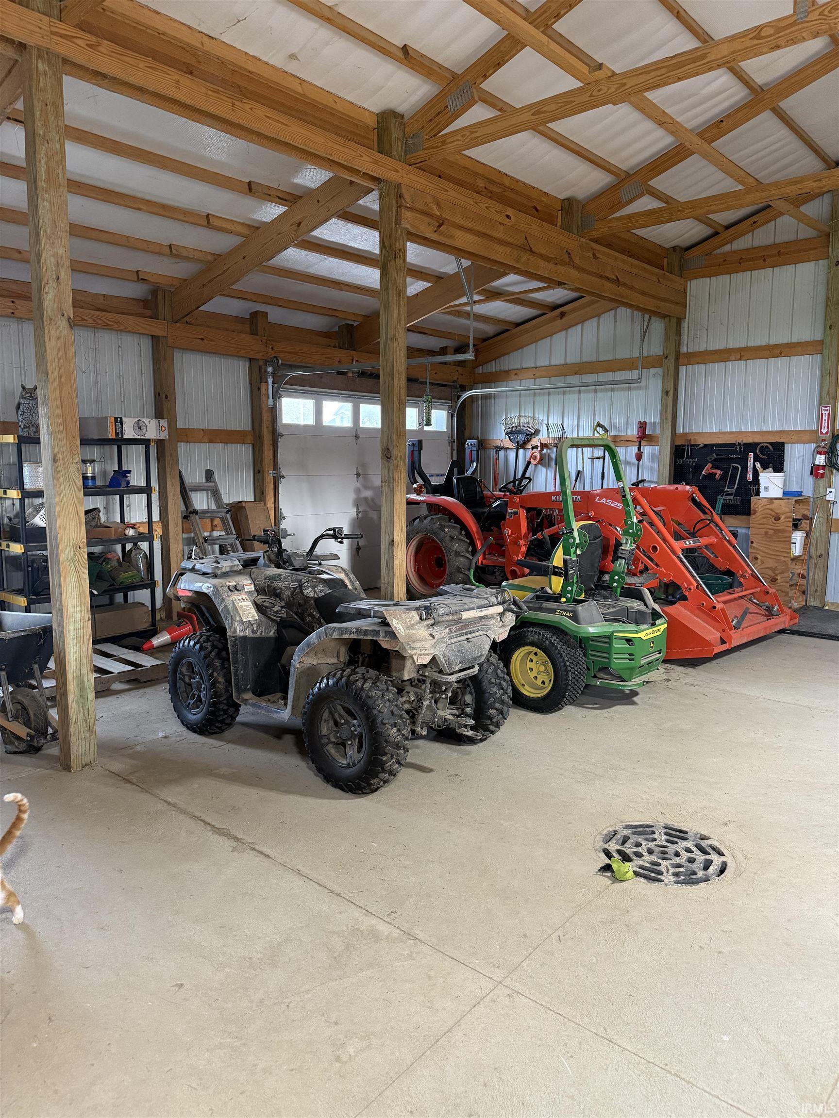 Spacious barn featuring a durable concrete floor, exposed wood beam construction, and corrugated metal wall panels