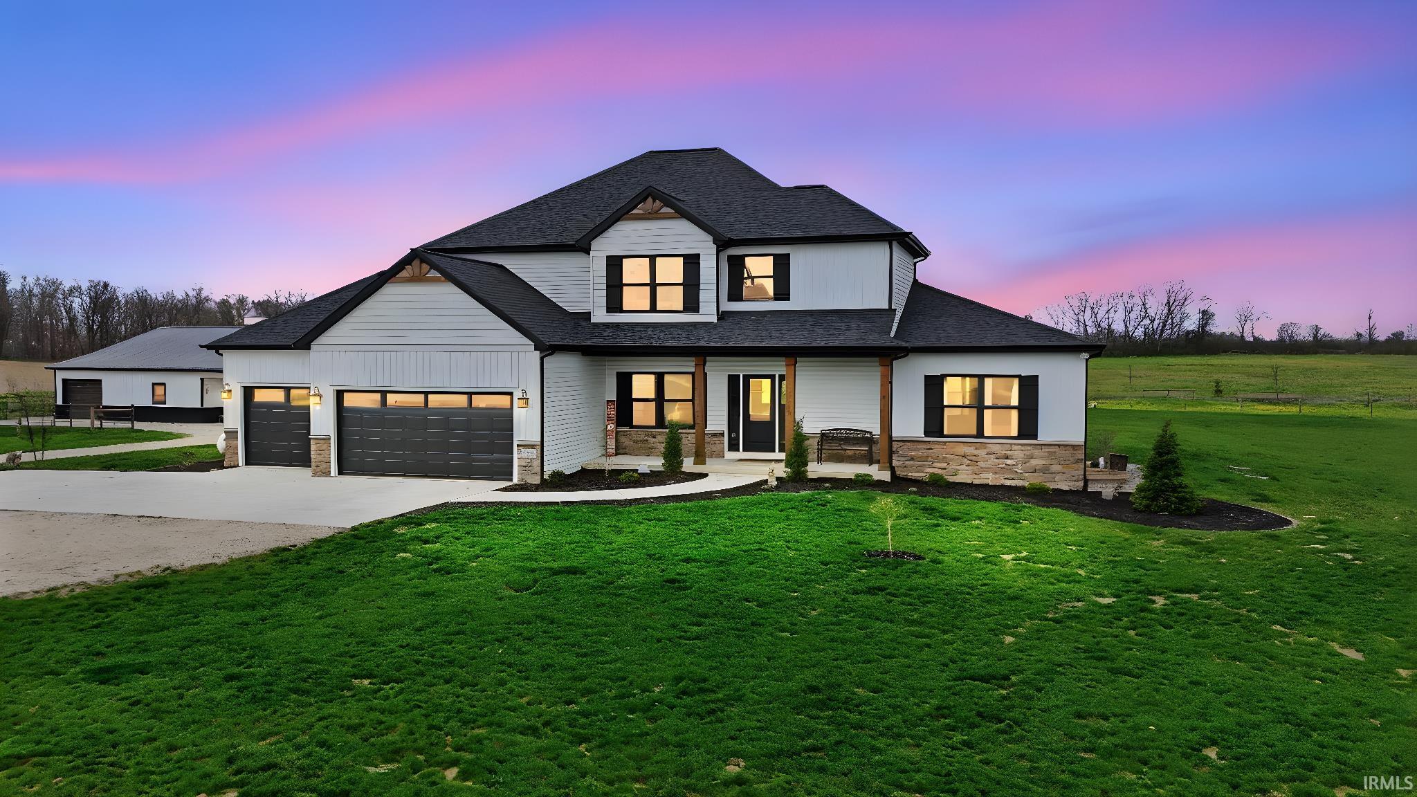 Modern inspired farmhouse with stone siding, a shingled roof, concrete driveway, a front yard, and an attached garage