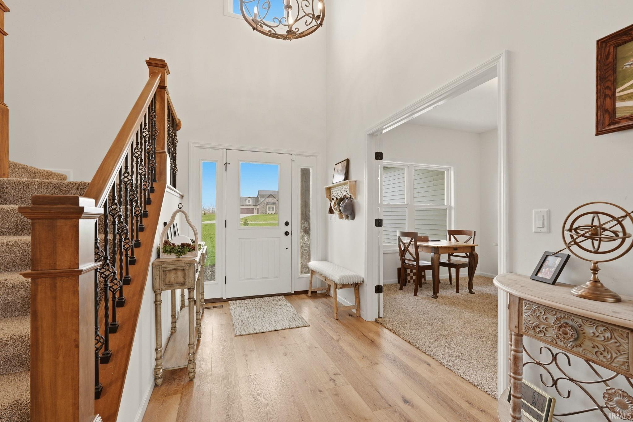 Foyer entrance featuring light wood-style flooring, a high ceiling, and a chandelier