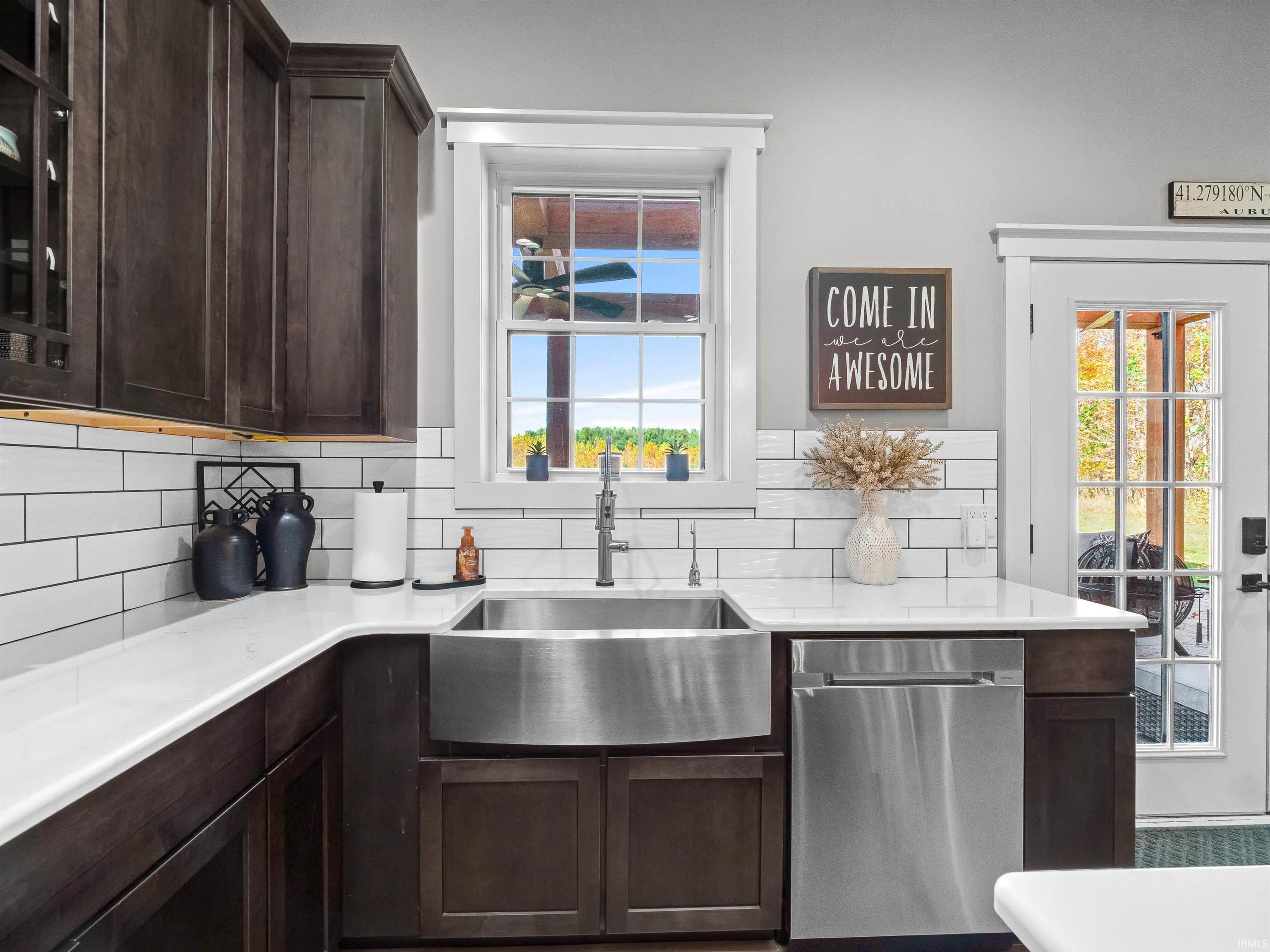 Kitchen with dark wood finish cabinets, stainless steel dishwasher, and glass fronted cabinets