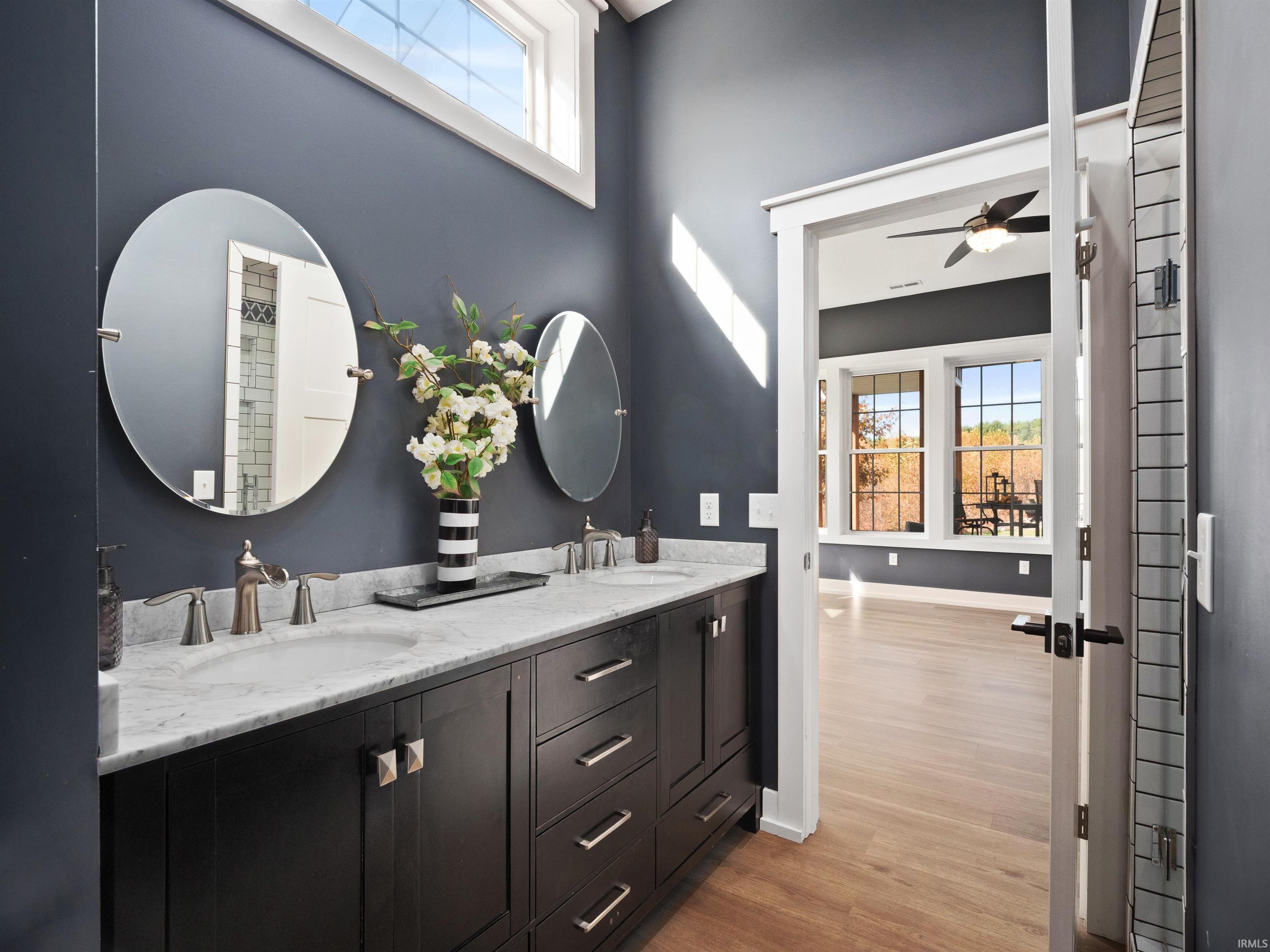 Full bath featuring plenty of natural light, double vanity, light wood-type flooring, and a ceiling fan