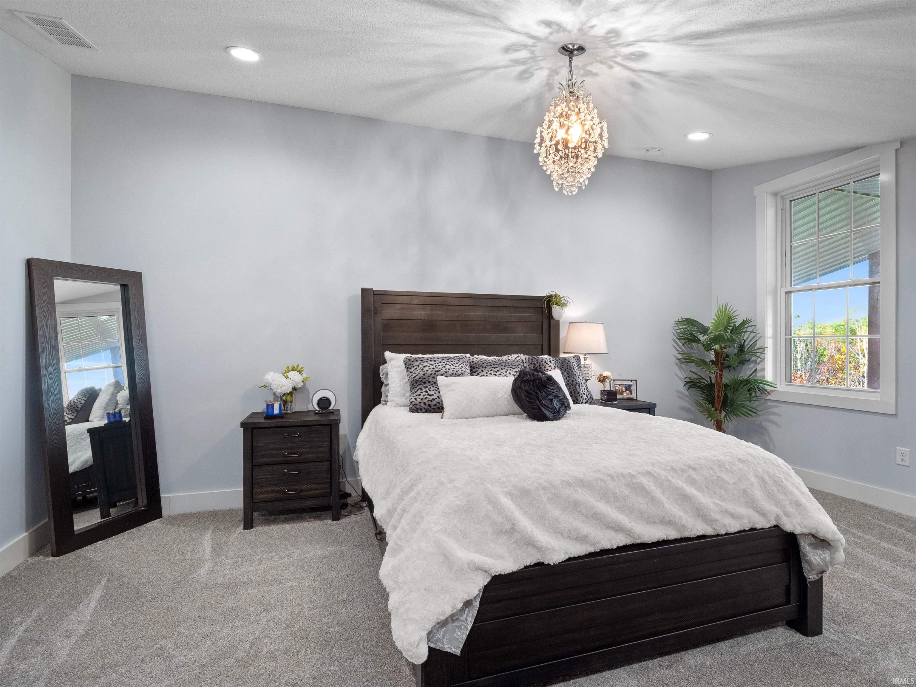 Bedroom featuring multiple windows, light carpet, and hanging lights
