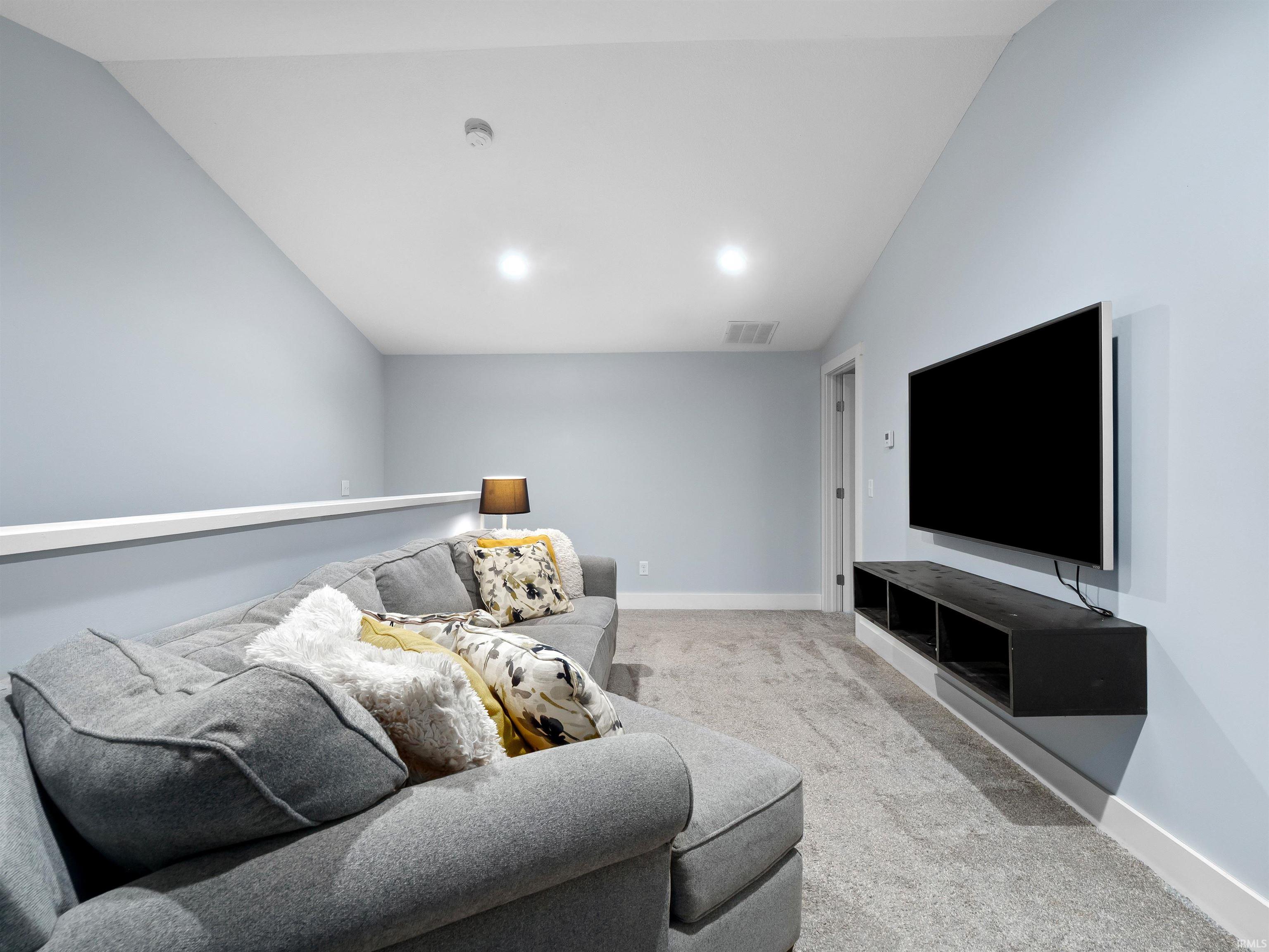 Living room with lofted ceiling and light carpet
