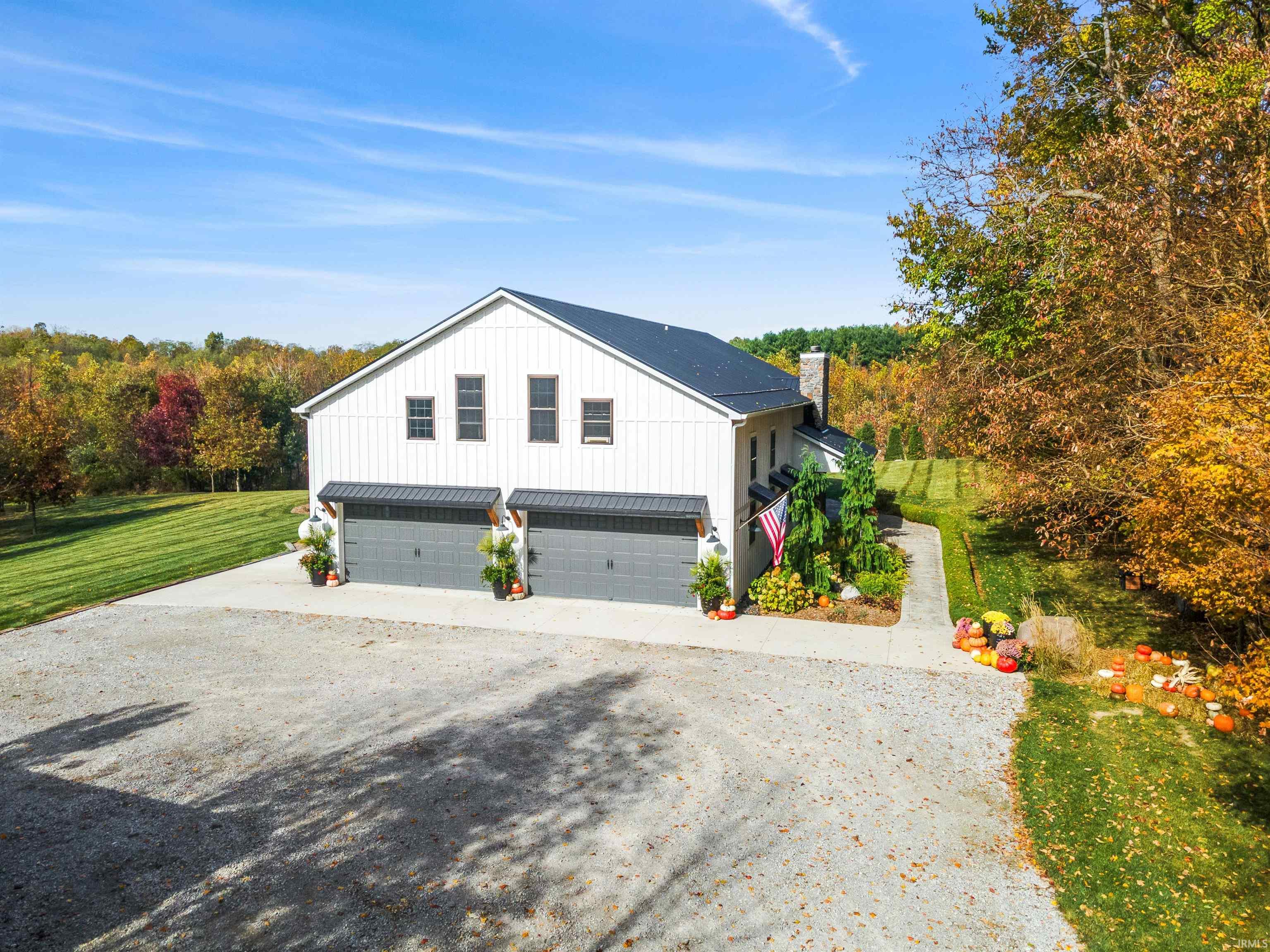 View of side of property with driveway, a chimney, a garage, a lawn, and board and batten siding