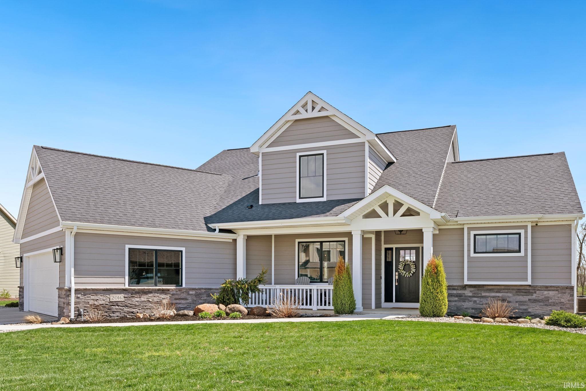 Craftsman-style house featuring stone siding, a front lawn, a porch, and roof with shingles