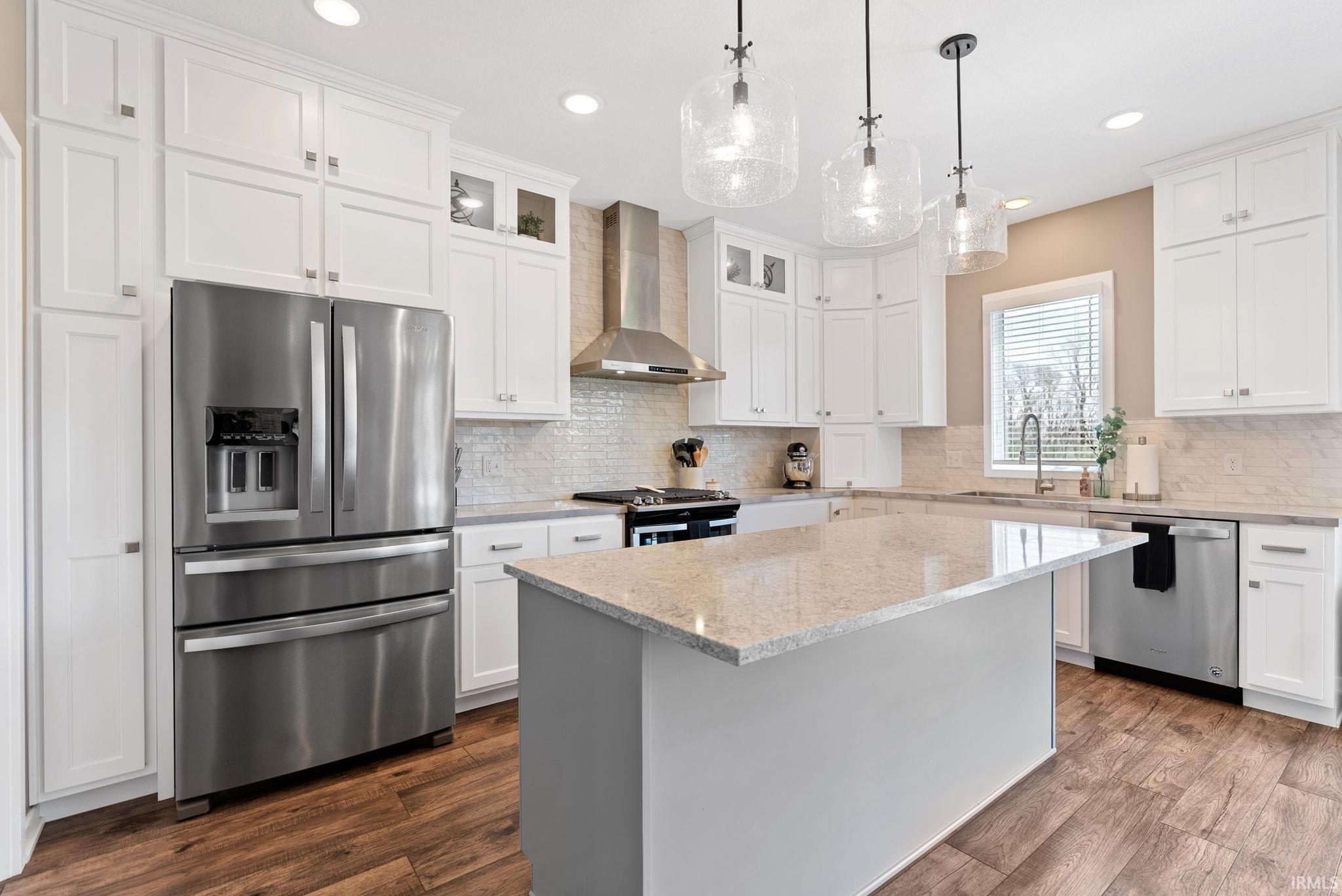 Kitchen with stainless steel appliances, glass fronted cabinets, light stone countertops, and white cabinets