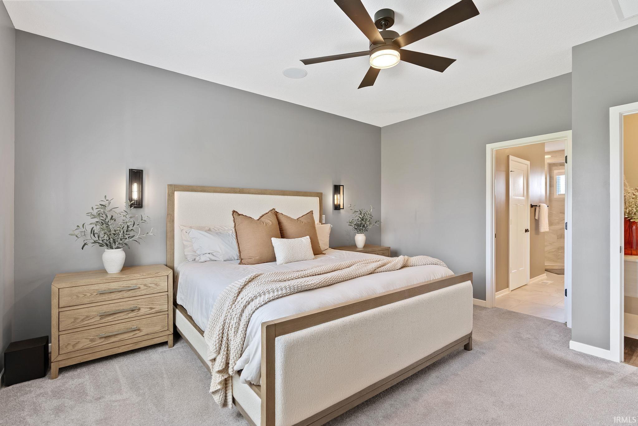 Bedroom with light colored carpet, connected bathroom, and ceiling fan
