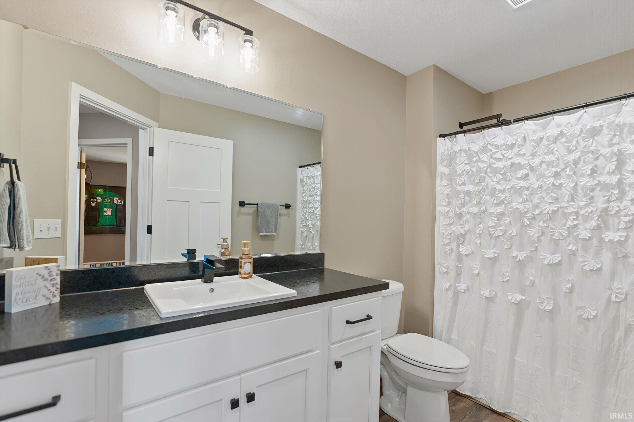 Bathroom with vanity, a shower with curtain, and dark wood-style floors