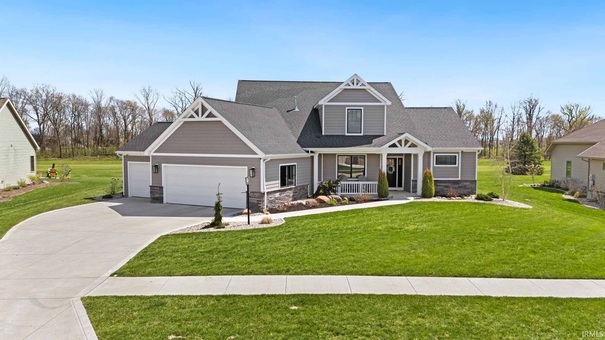 Craftsman-style home with an attached garage, covered porch, stone siding, a front lawn, and a shingled roof