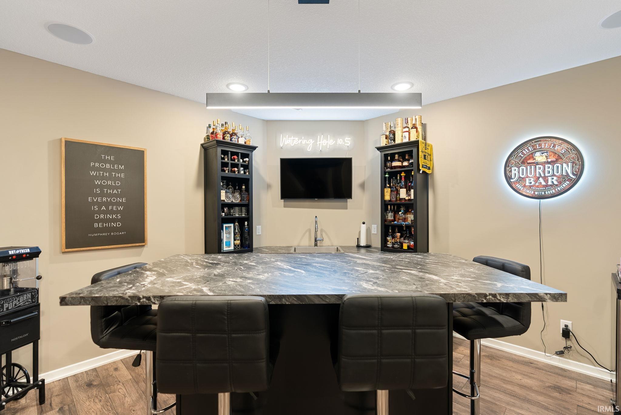 Indoor bar with dark countertops and wood finished floors