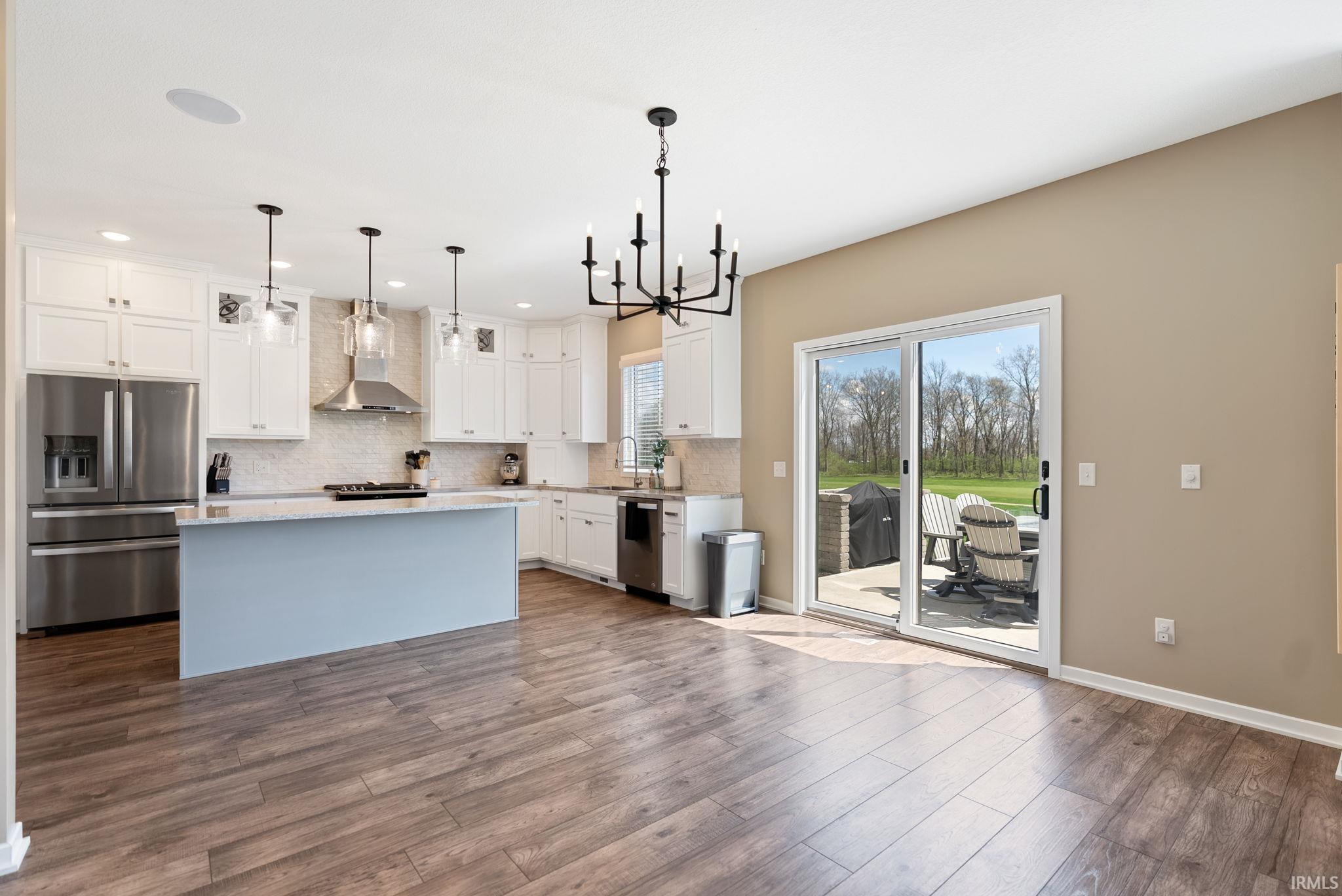 Kitchen featuring stainless steel appliances, a chandelier, white cabinetry, and a kitchen island