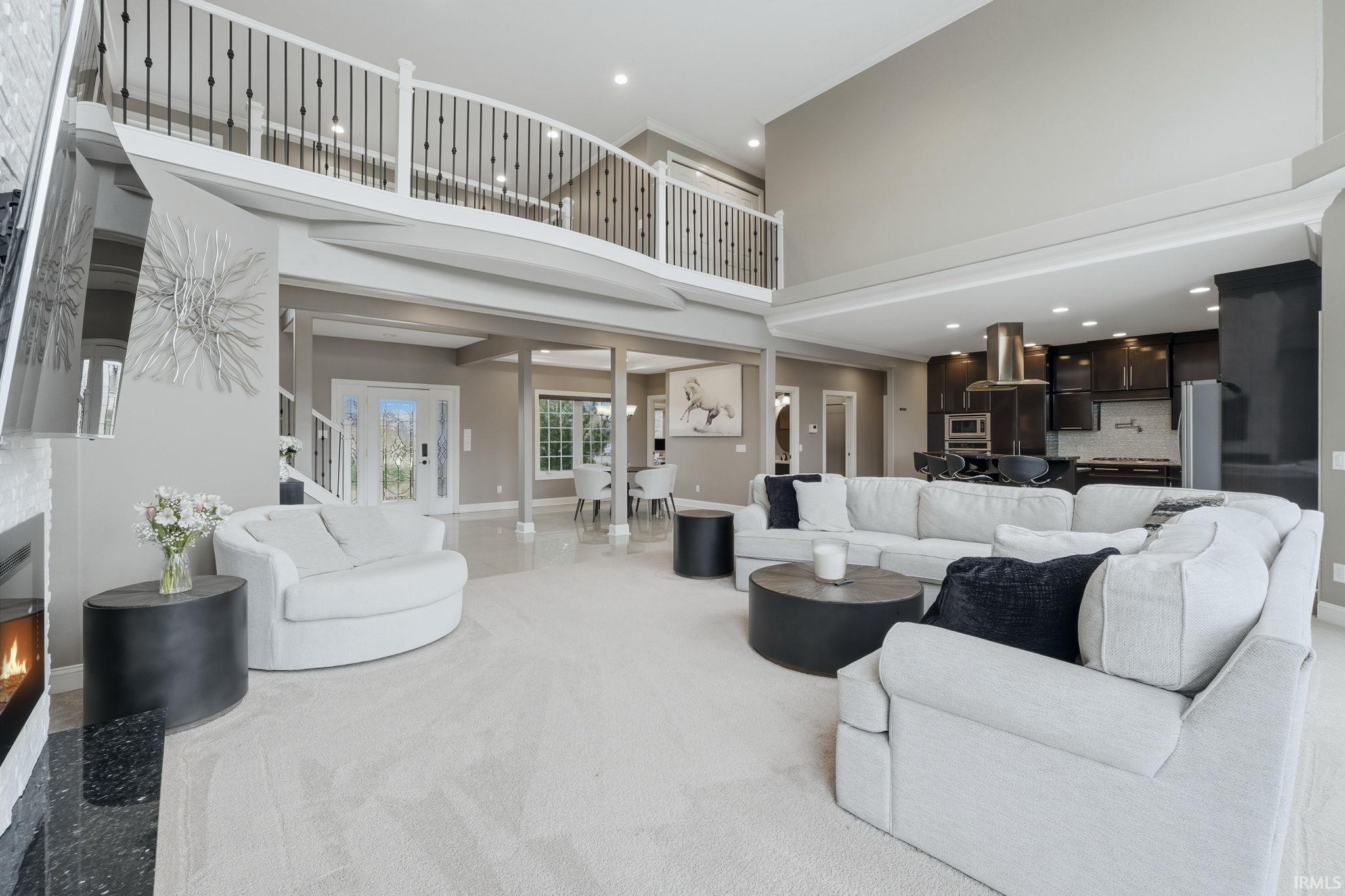 Carpeted living area featuring a high ceiling, recessed lighting, and a warm lit fireplace