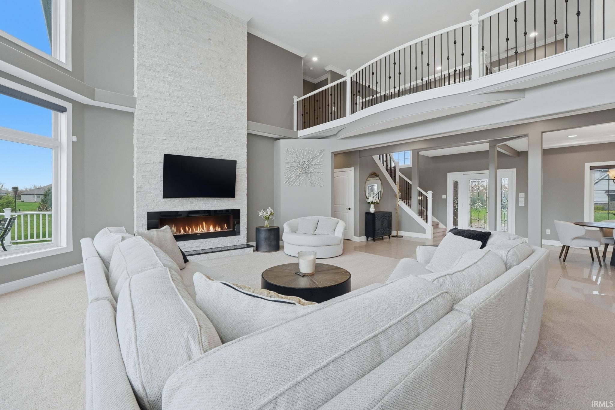 Living room featuring a high ceiling, a fireplace, light carpet, and recessed lighting