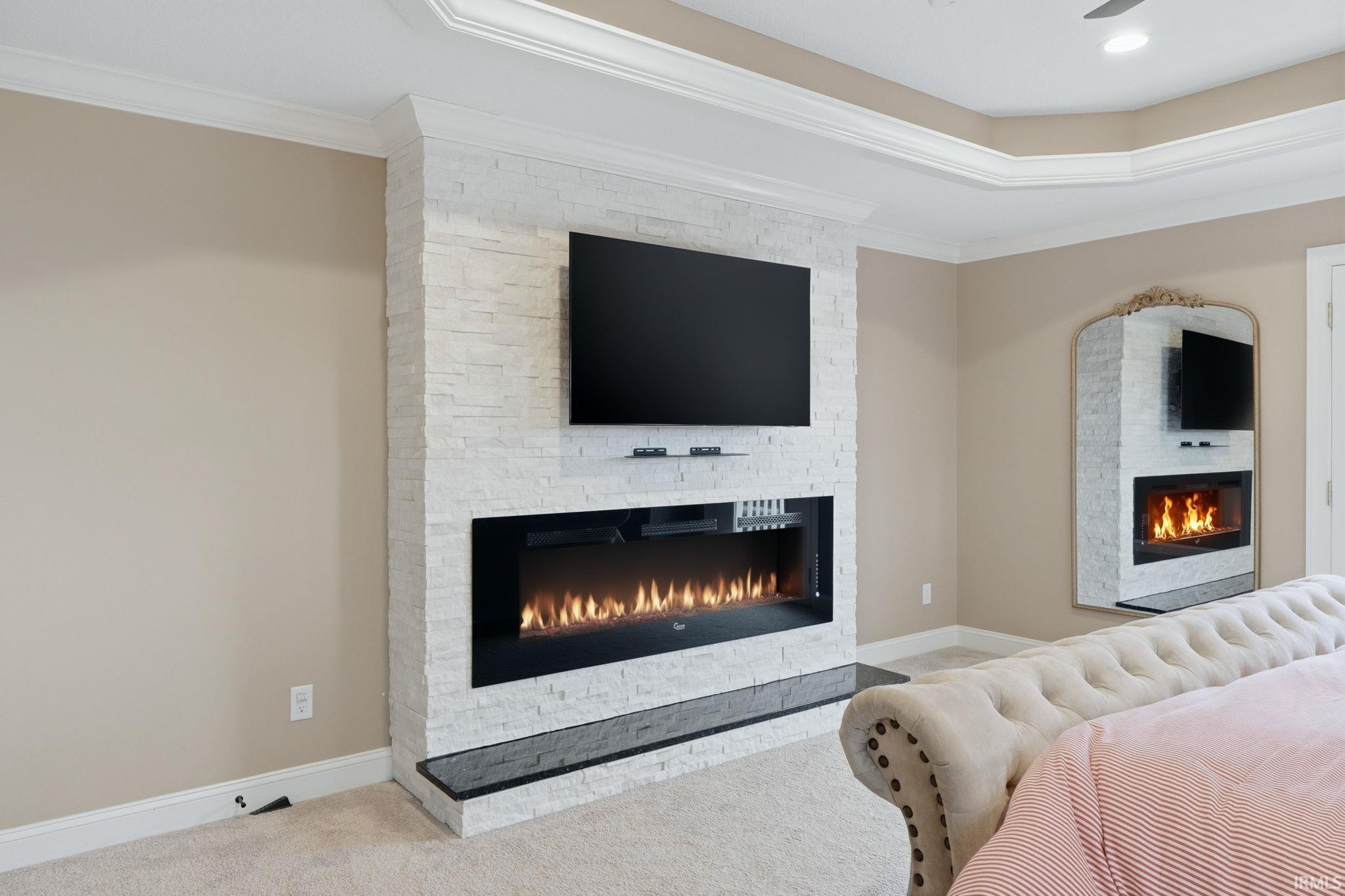 Bedroom with a fireplace, crown molding, and light colored carpet