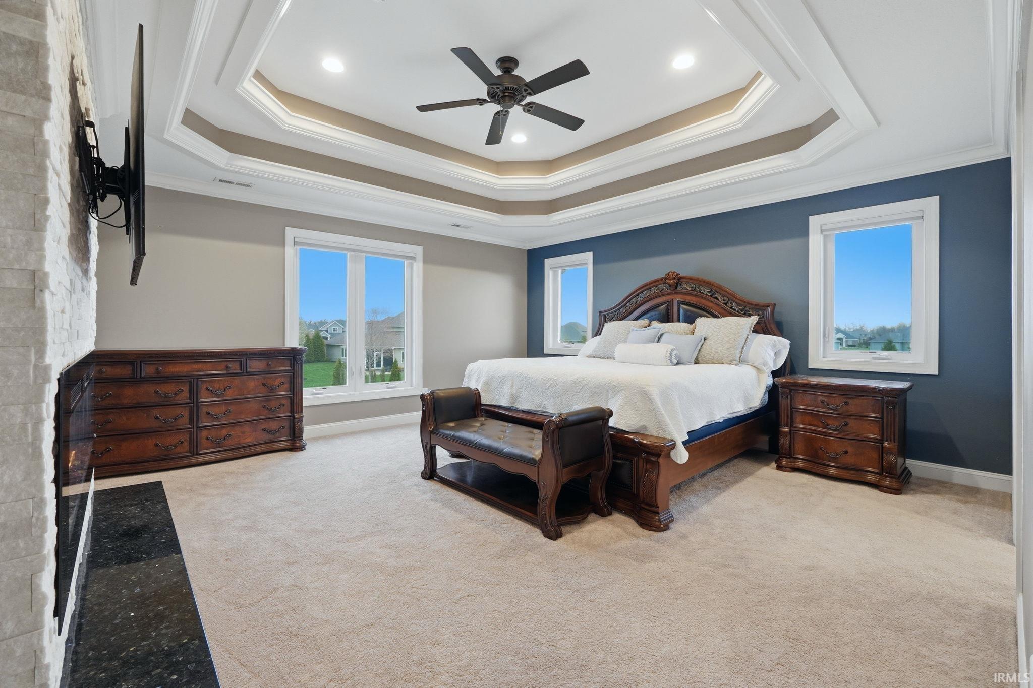 Bedroom with ceiling fan, light colored carpet, crown molding, a warm lit fireplace, and recessed lighting